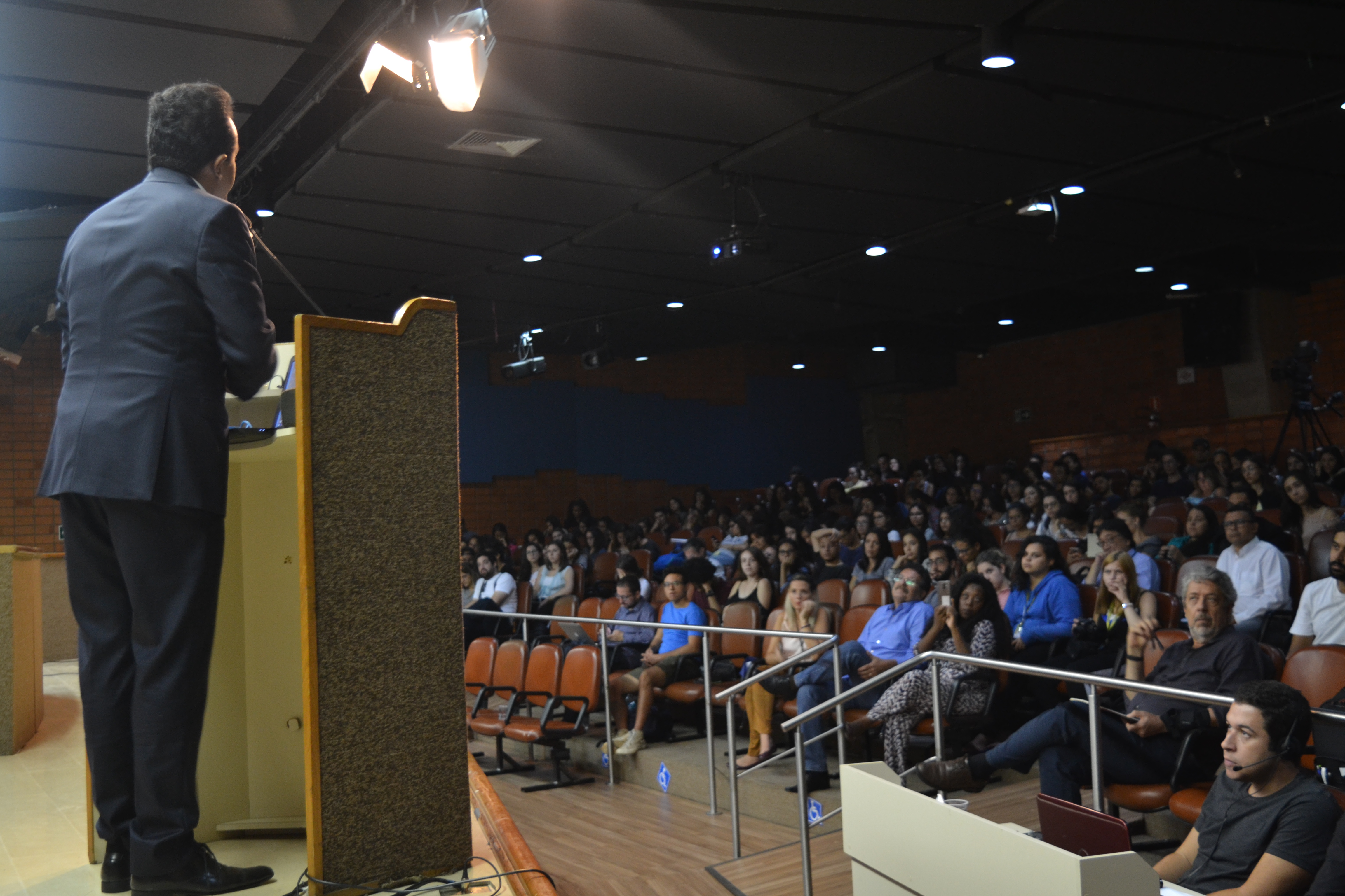 Foto do subprefeito, Gilmar Souza Santos, palestrando, direto do palco, para o auditório cheio da Universidade São Judas Tadeu.