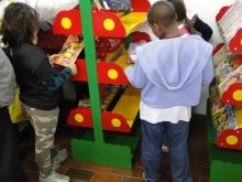 Crianças procuram livros na sala de leitura.