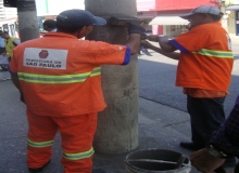 Funcionários pintam postes por conta dos lambe-lambes