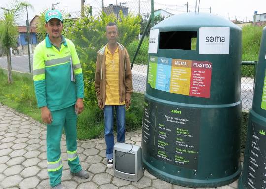 Seo Natalino e o funcionário da Soma levam aparelho de tv até a caçamba de produots eletrônicos