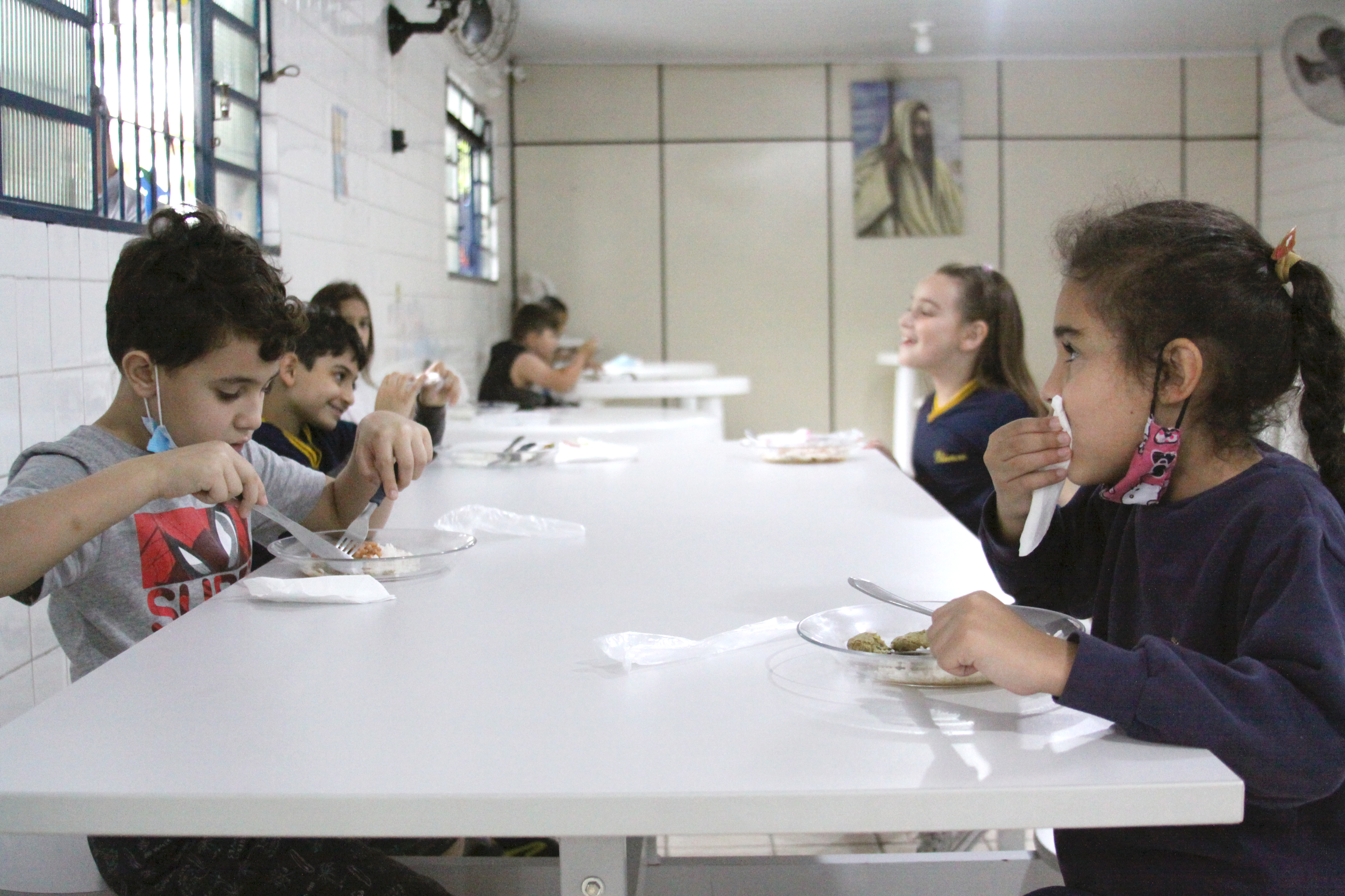 Cinco crianças sentadas durante refeição