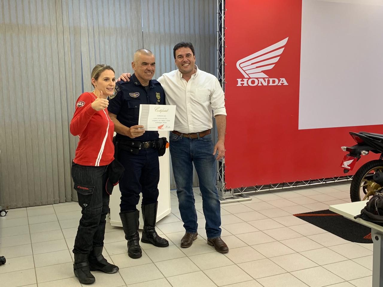 Secretário Luiz Alvaro ao lado de um funcionário da Guarda Civil Metropolitana que está recebendo seu certificado pelo curso, junto com uma representante da Honda.