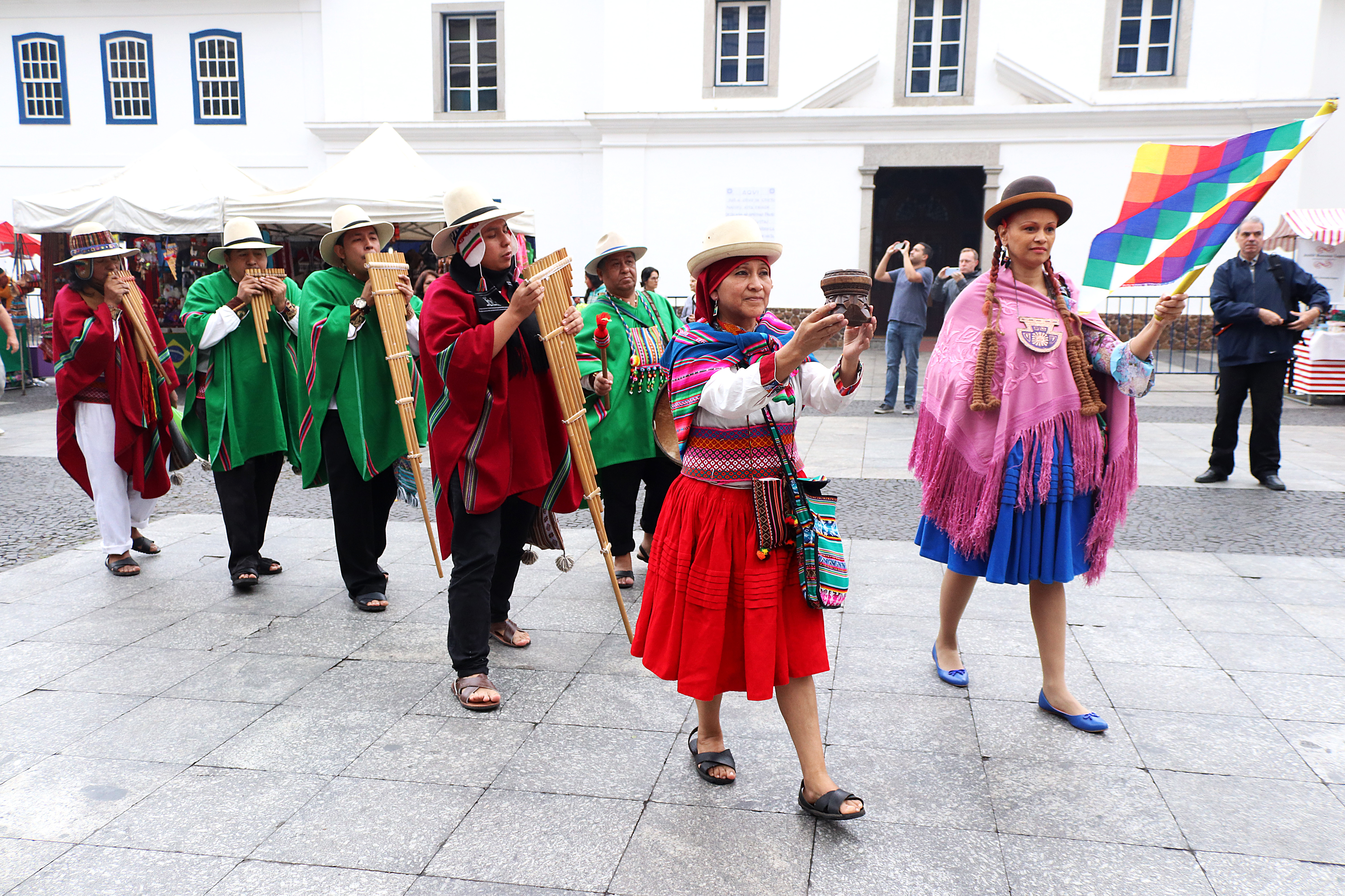 Grupo musical peruano se apresenta na abertura no evento, com roupas coloridas e instrumentos típicos do país.