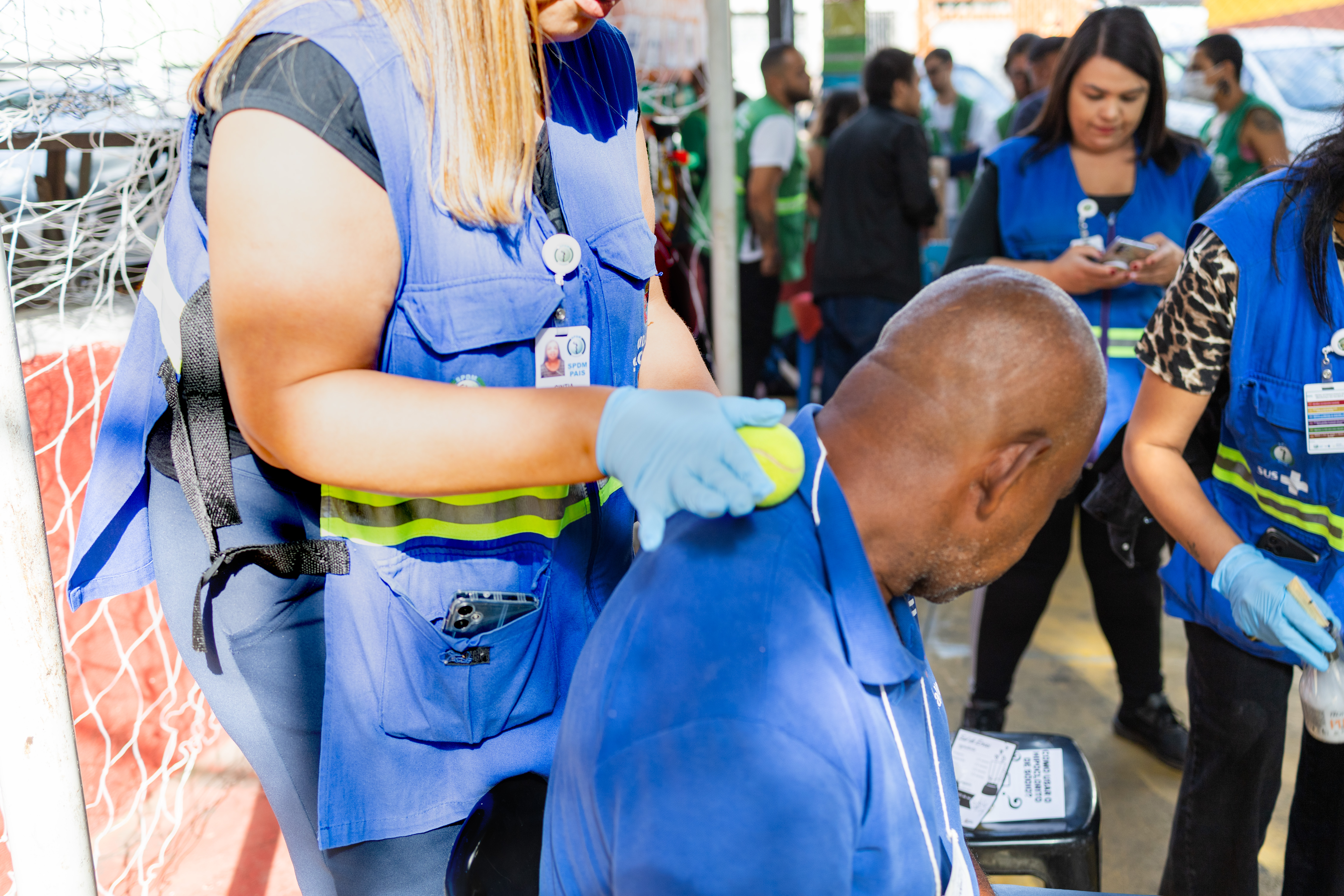 A imagem mostra uma Assistente Social de Saúde fazendo massagem em um catador de materiais recicláveis