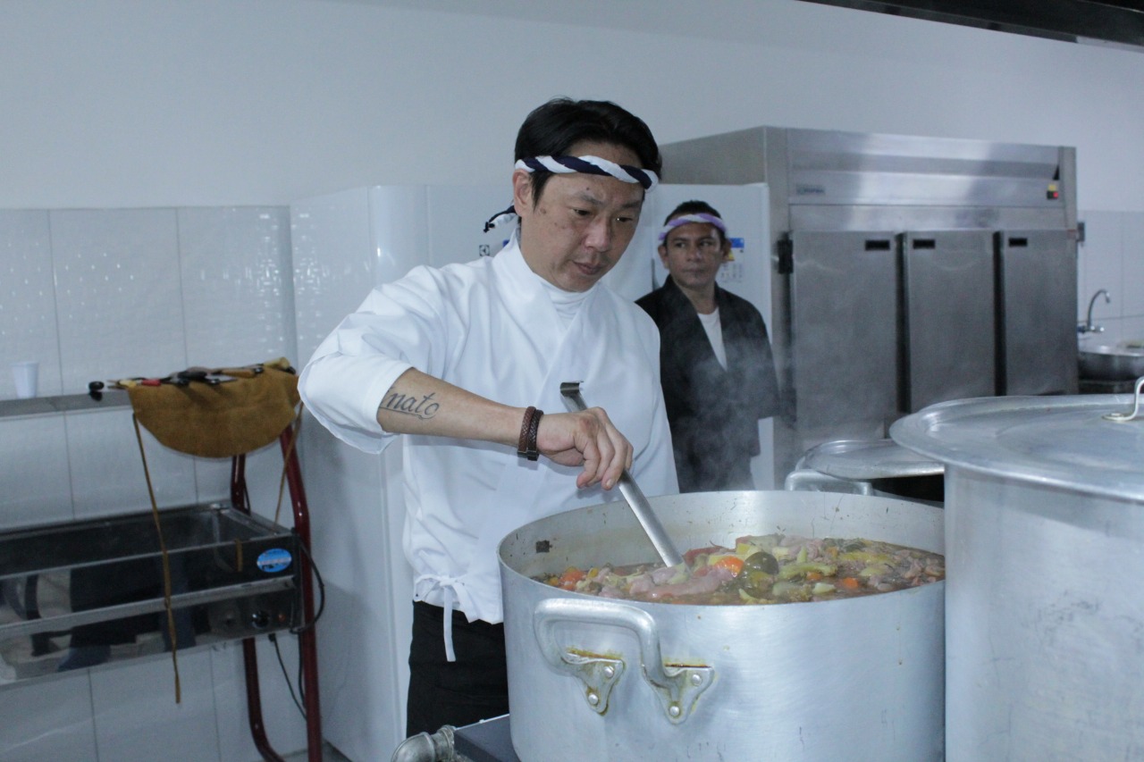  Um dos chefs de cozinha está mexendo um caldeirão de sopa de legumes na cozinha.