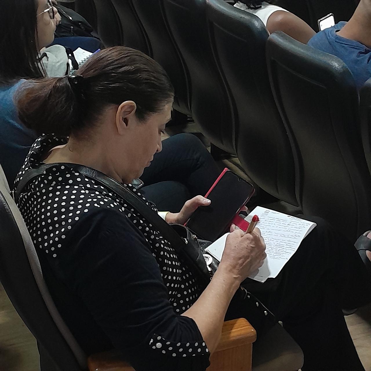 Mulher faz anotações durante seminário