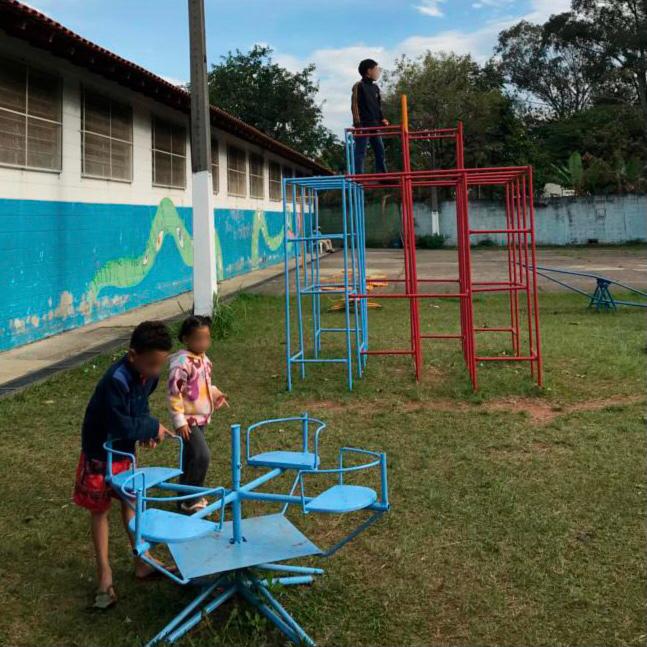 Três crianças brincando na parte externa do serviço direcionada para a recreação delas. As crianças estão com o rosto borrado por motivos de segurança. 