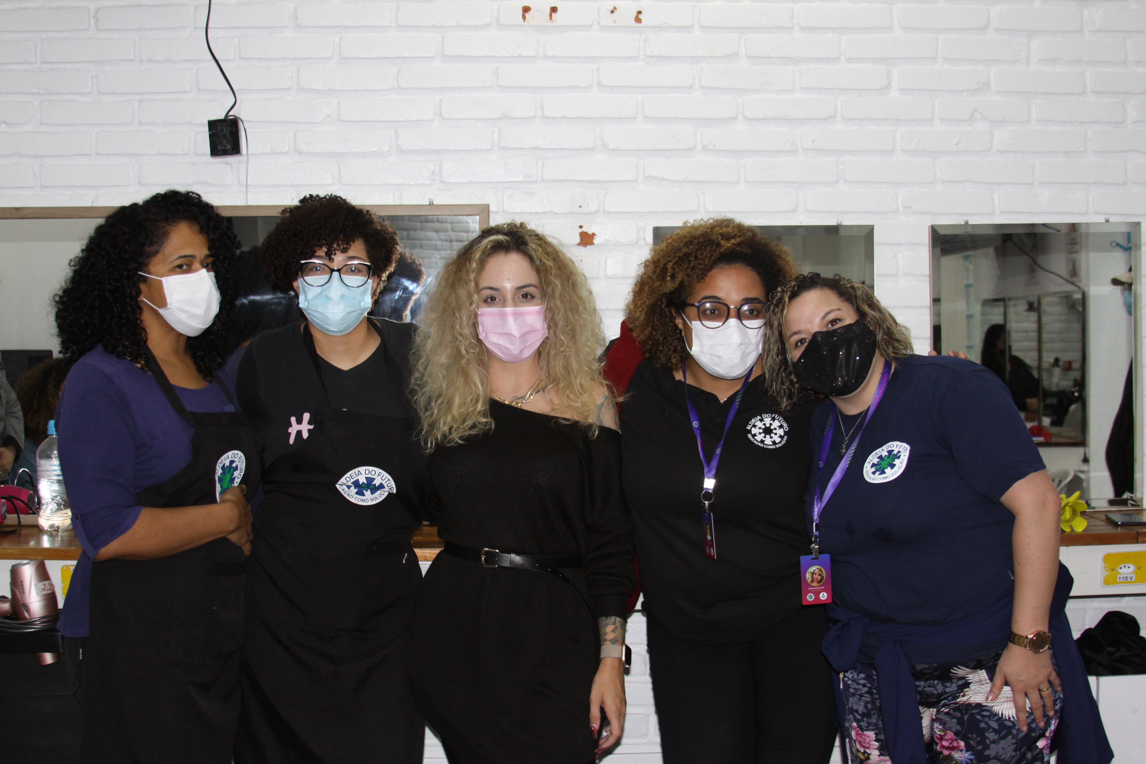 5 mulheres reunidas de mascará, no meio tem a professora voluntária e ao redor as alunas. 