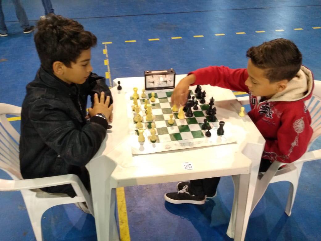 Duas crianças jogam xadrez em uma mesa