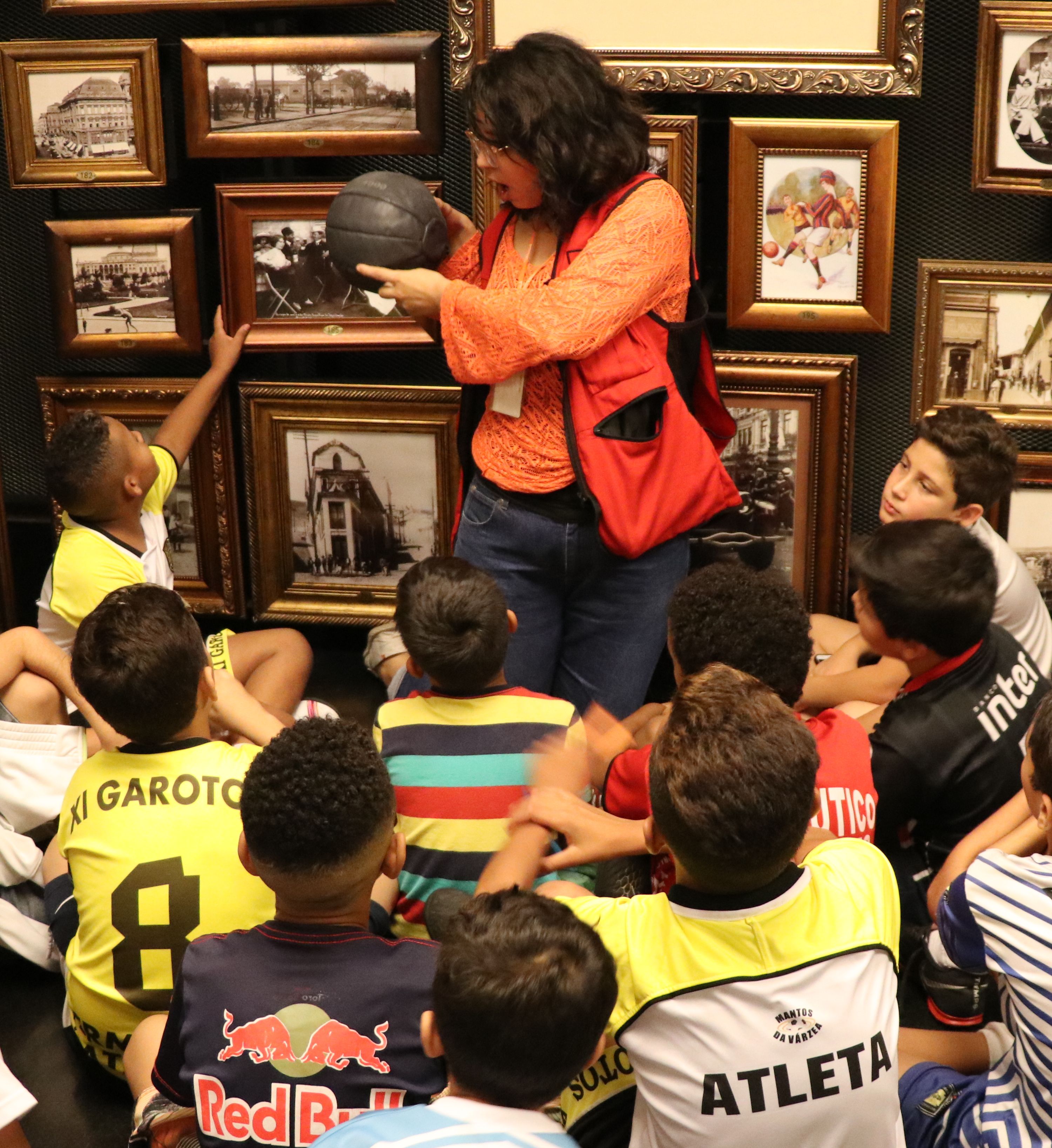 Crianças sentadas no chão dentro da sala no Museu do Futebol .