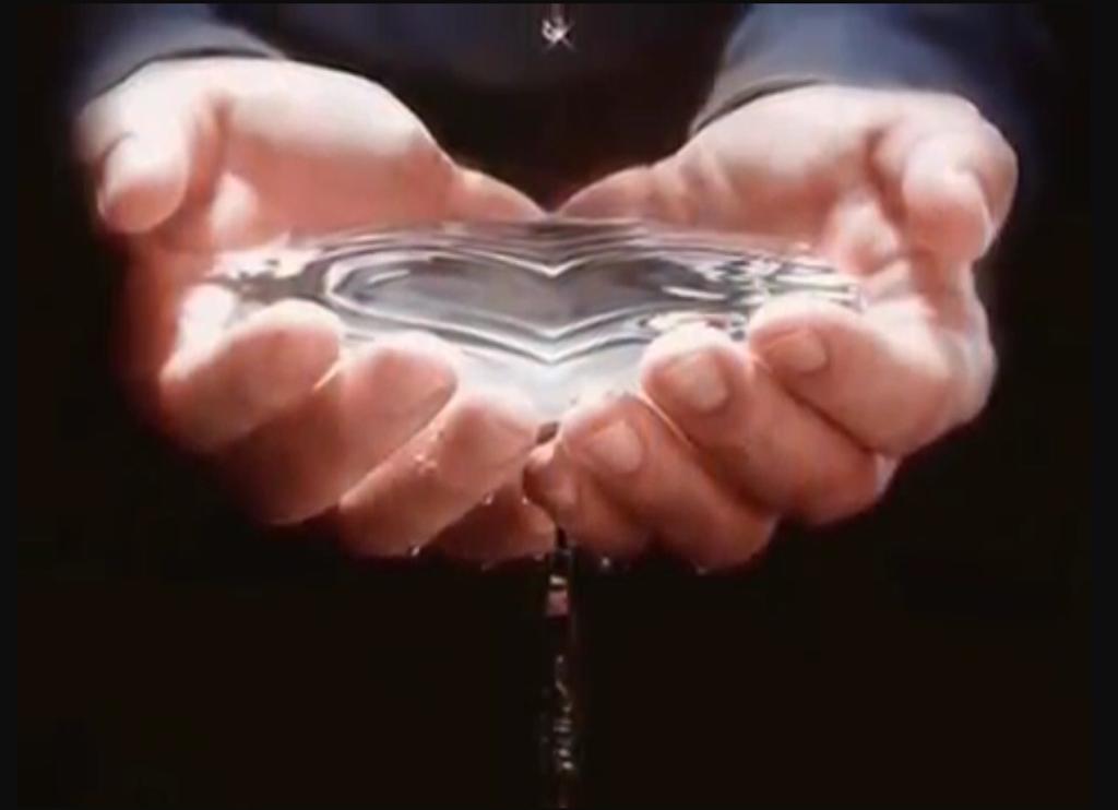Descrição de uma mãe segurando água em formato de coração.