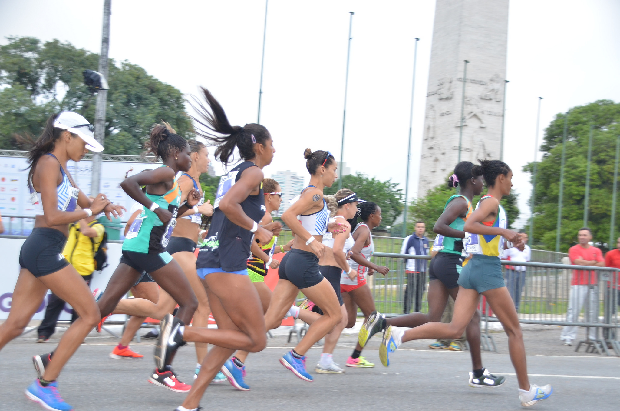 Na imagem, um grupo de corredoras corre, e o Obelisco de São Paulo está ao fundo