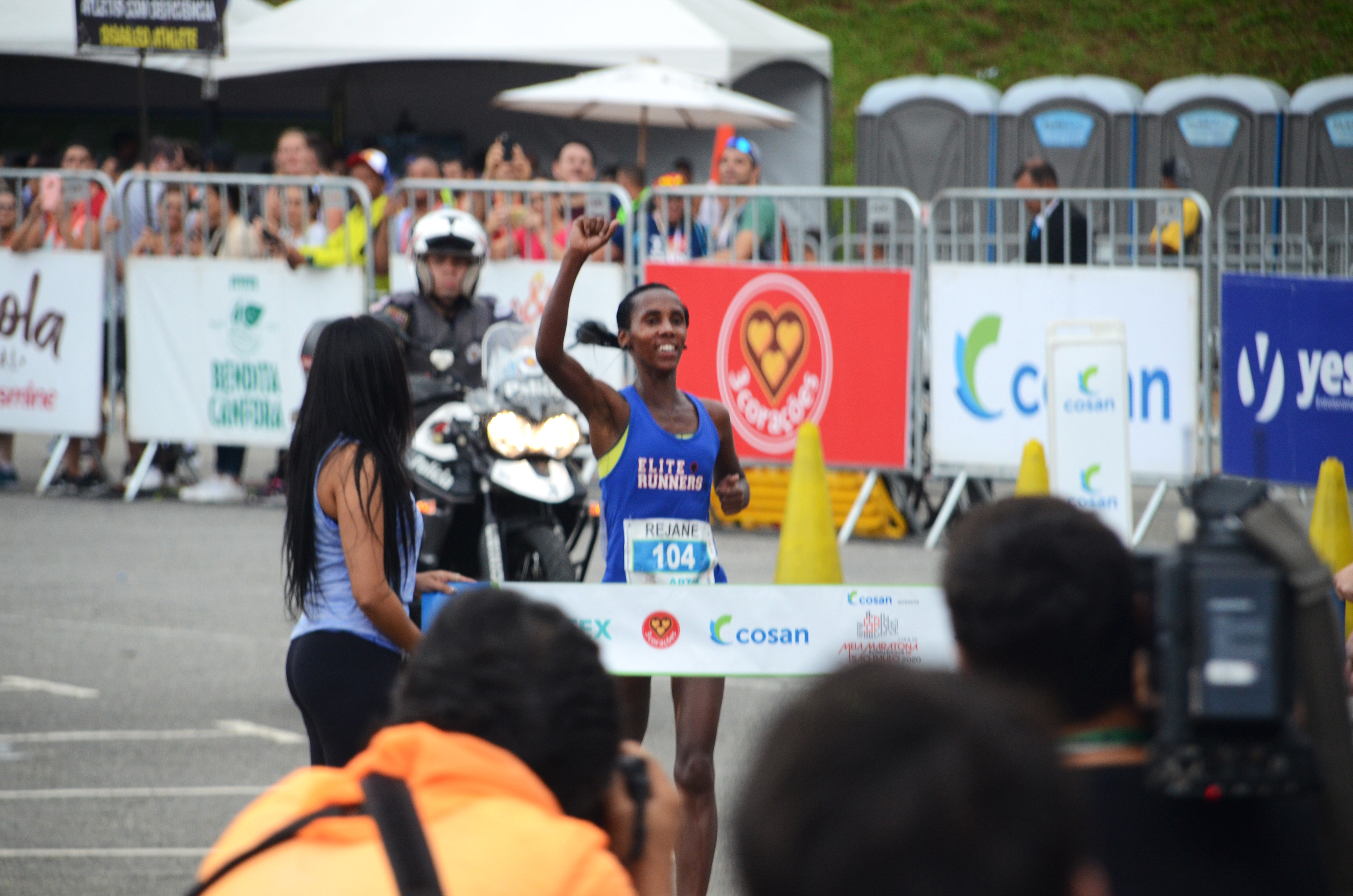 Rejane Ester da Silva, segunda colocada da Meia Maratona Internacional de São paulo no momento da sua chegada, com o punho direito cerrado no alto.