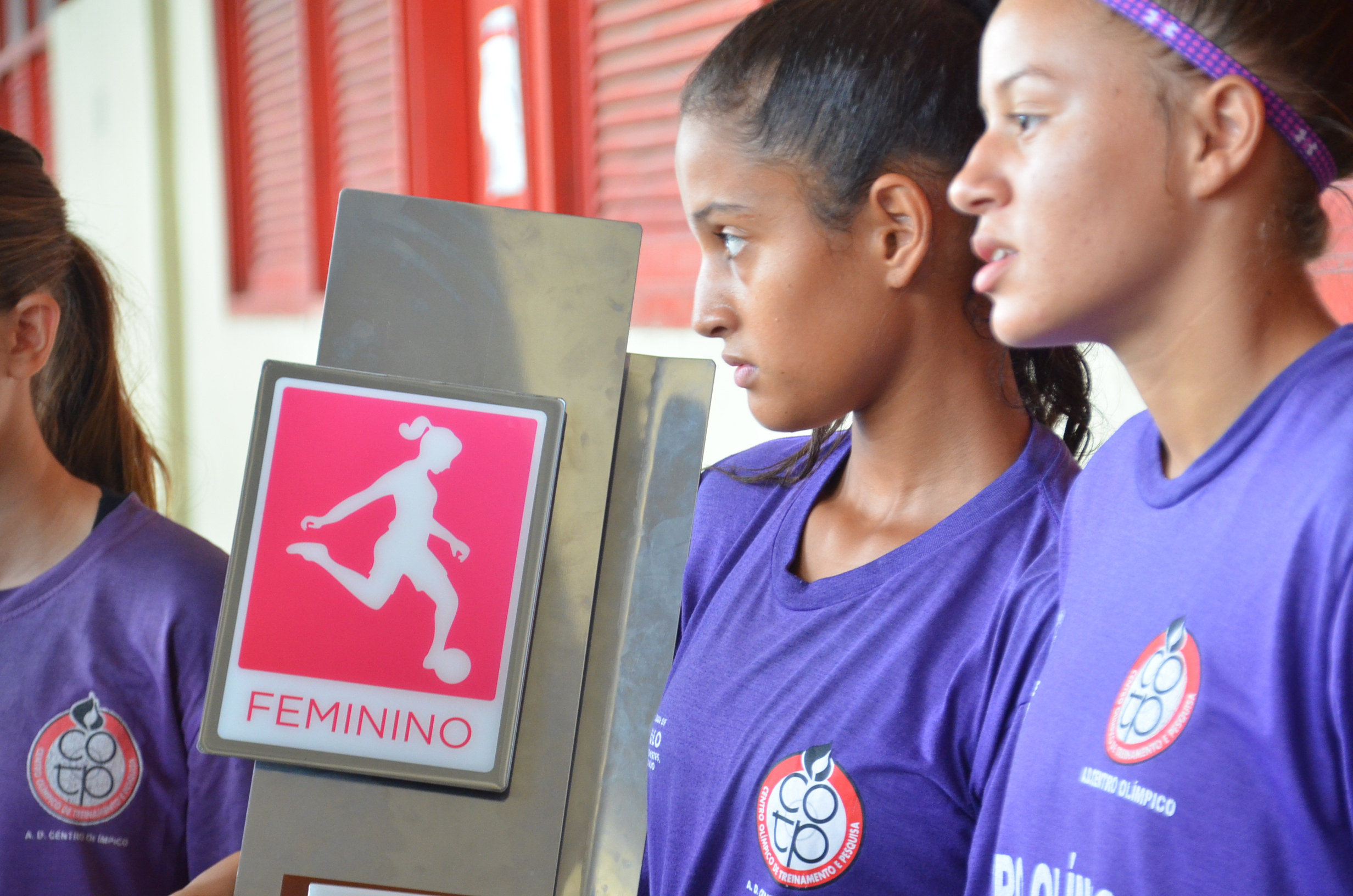 Meninas do futebol com uma placa em foco escrito "feminino" e uma arte de mulher jogando