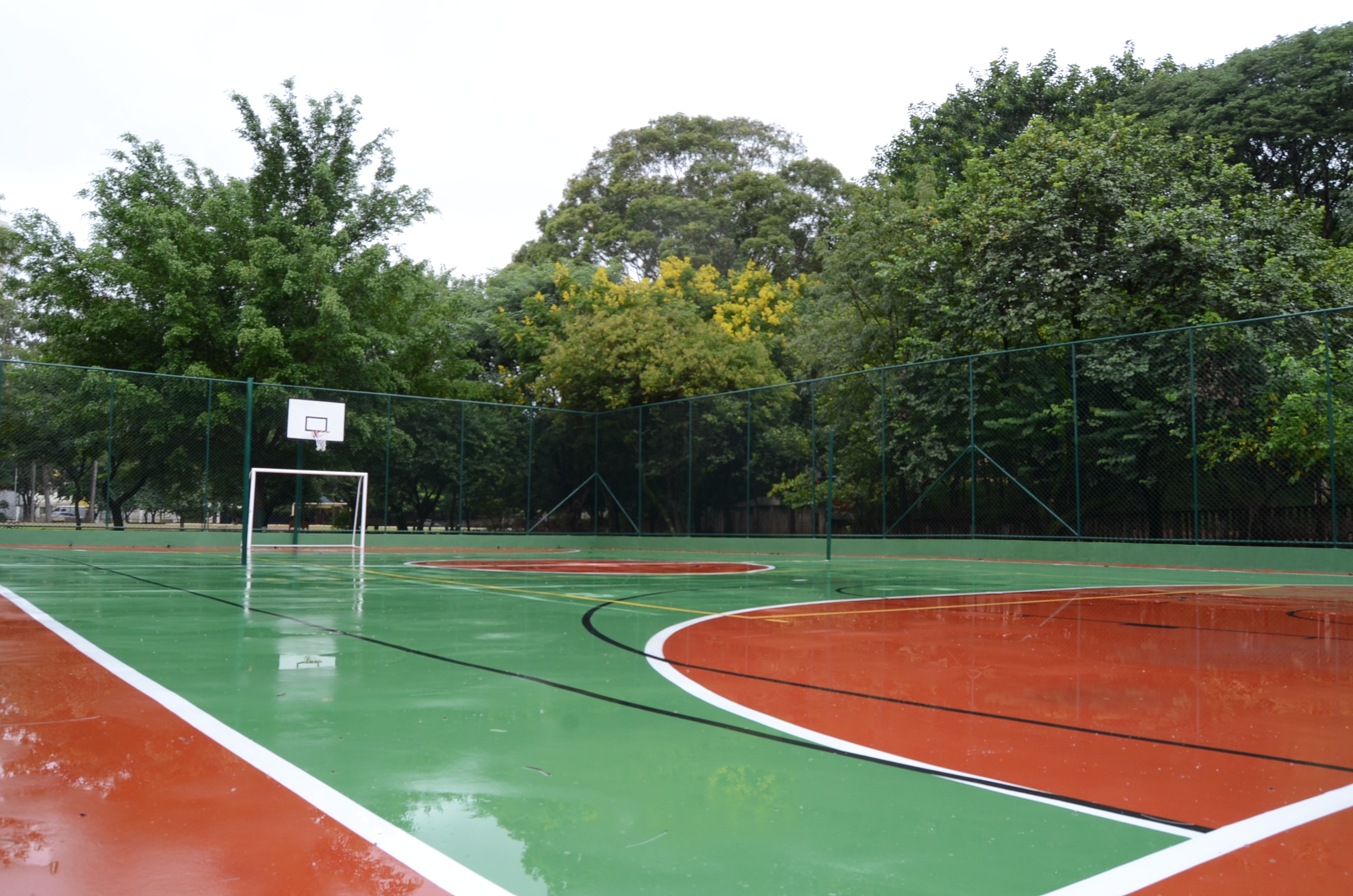 Na foto, uma quadra poliesportiva ao ar livre, com árvores ao fundo, localizada no Centro Esportivo Vila Alpina.