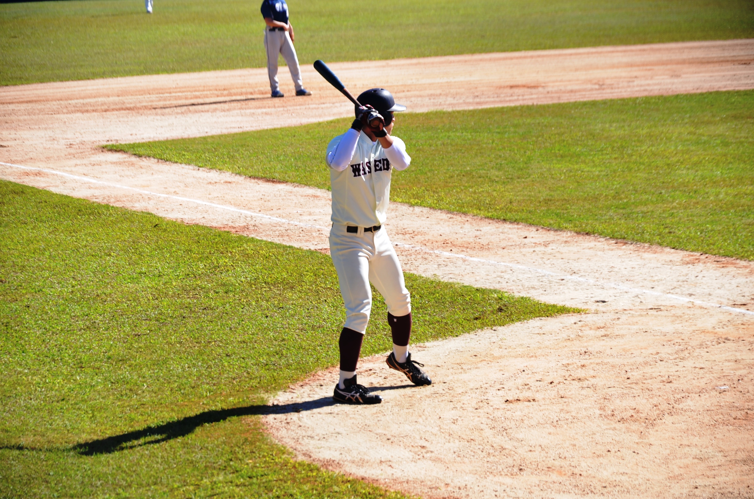Jogador segurando taco de beisebol no campo.