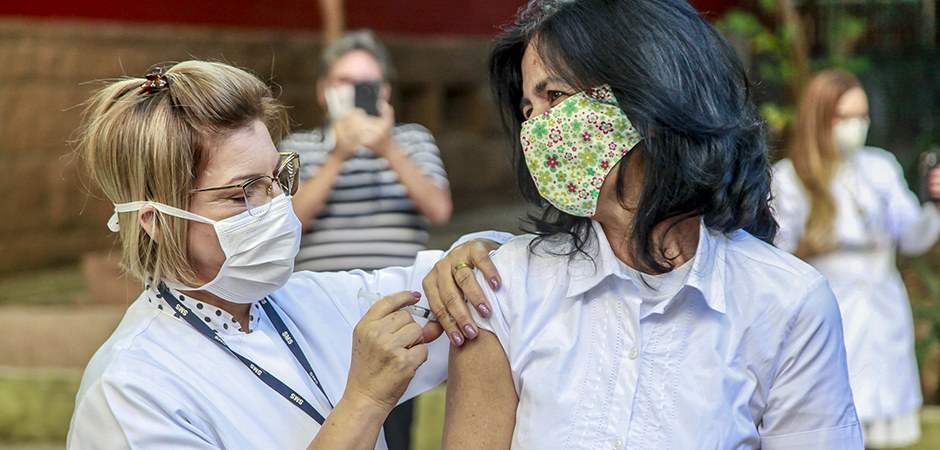 Foto de uma enfermeira aplicando vacina em uma pessoa.
