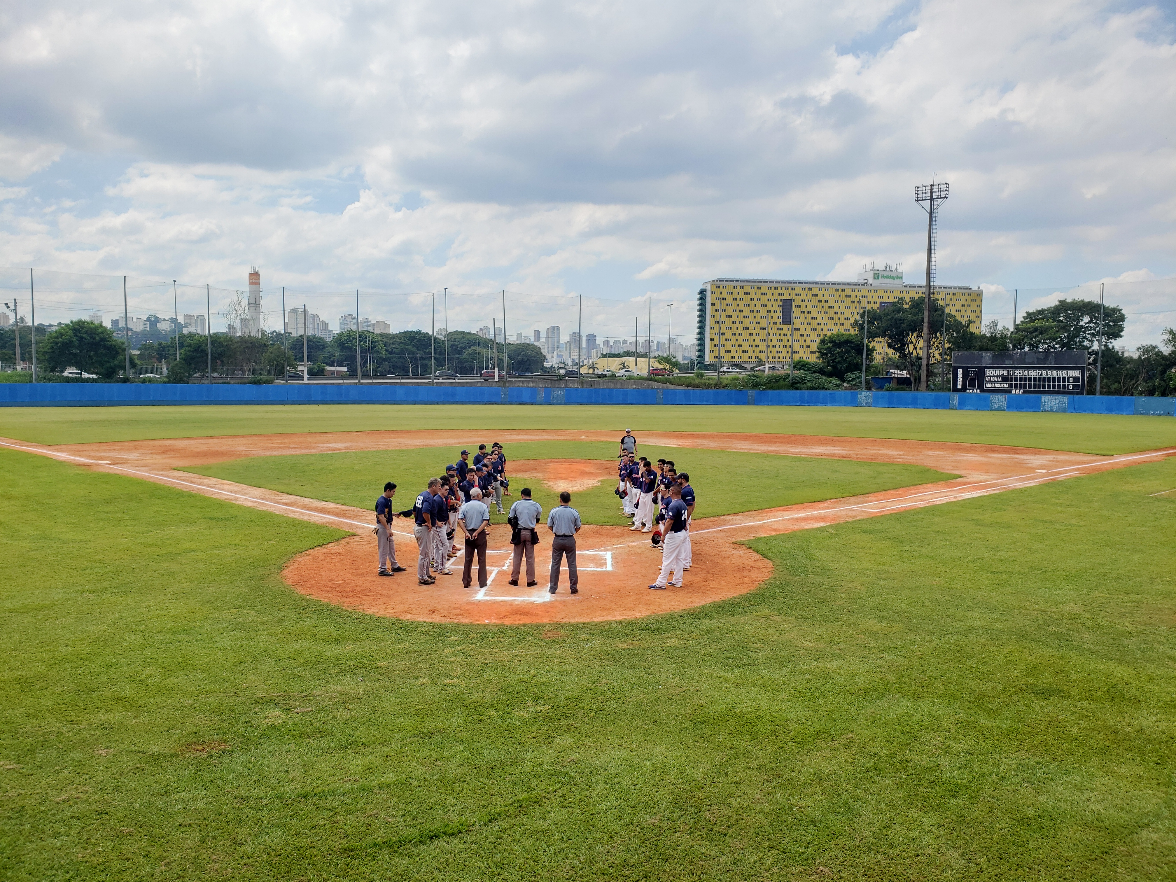Atletas e árbitros de beisebol perfilados em dois grupos no campo de beisebol do Mie Nishi.