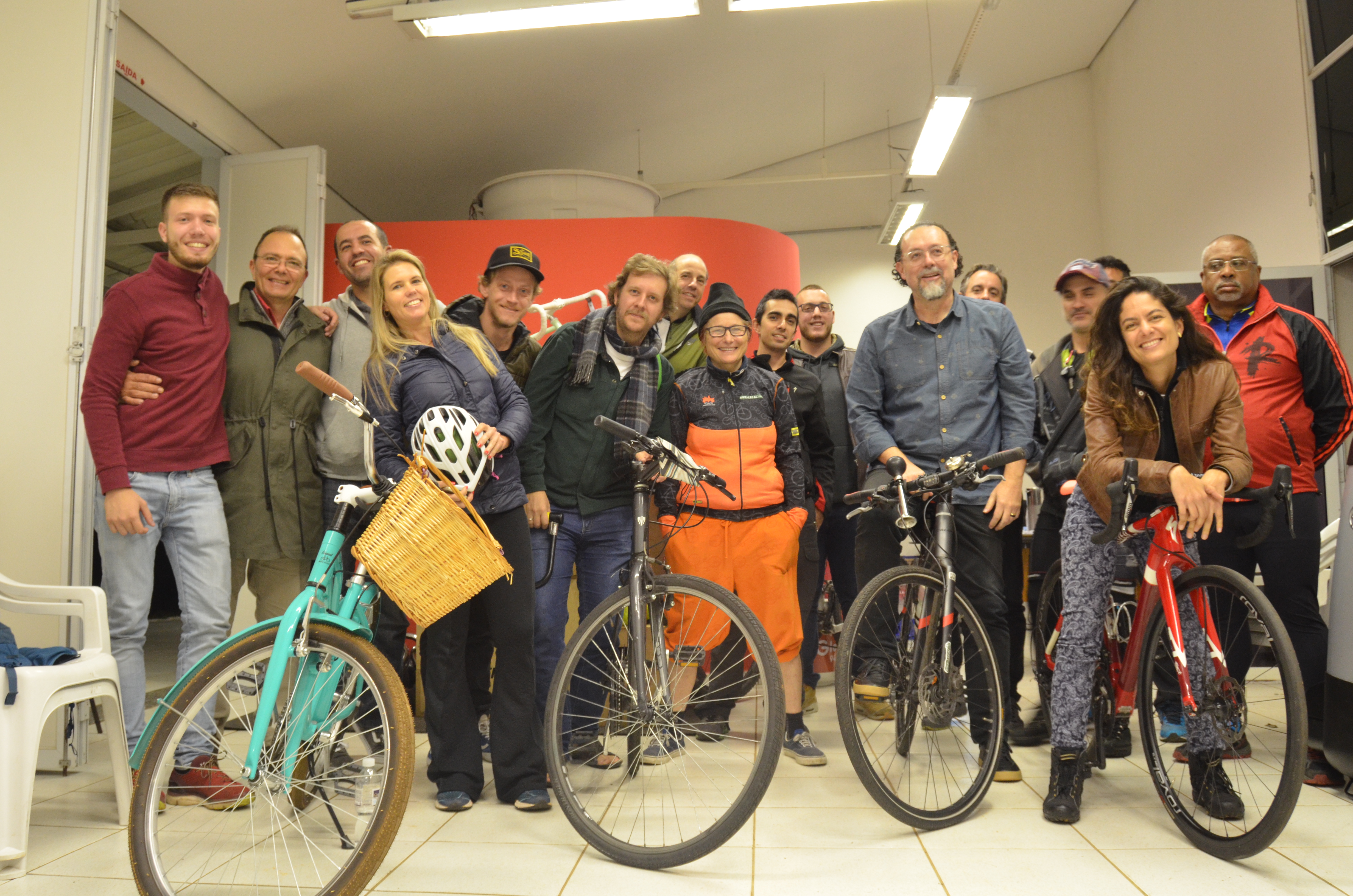 Ciclistas e servidores da Secretaria Municipal de Esportes e Lazer posam para foto com bicicletas dentro de uma sala.