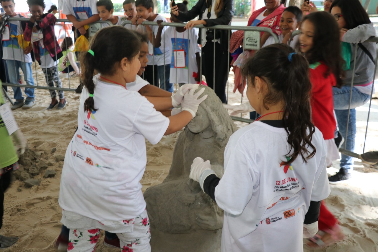 Crianças destruindo a estátua de areia