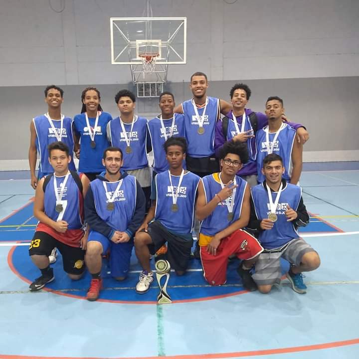 Atletas de basquete na quadra com o troféu de terceiro lugar do evento Virando o Jogo. 