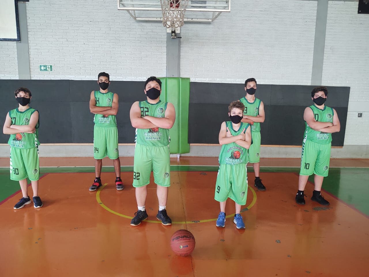 Atletas da Escola Presbiteriana Erasmo Braga, do Mato Grosso do Sul, posam para foto dentro de quadra de basquete. Todos estão de máscara.