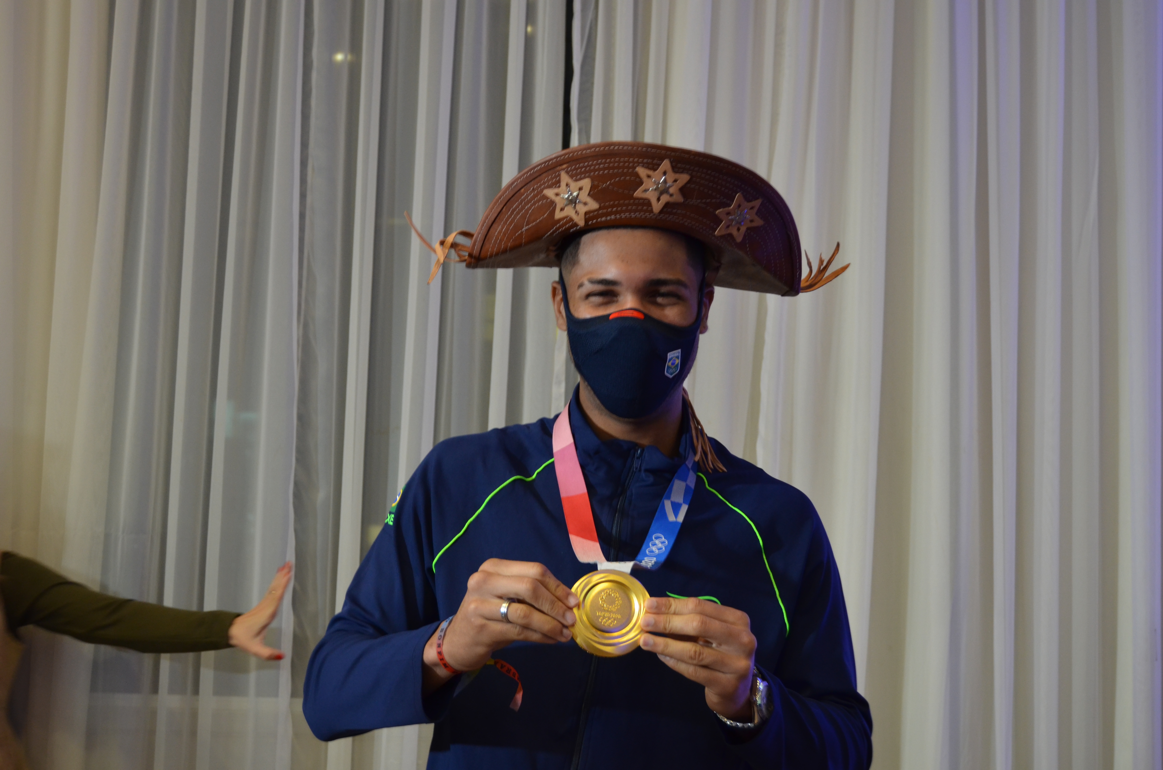 Na imagem, Hebert Conceição campeão olímpico, com a medalha na mão e o chápeu de cangaçeiro.