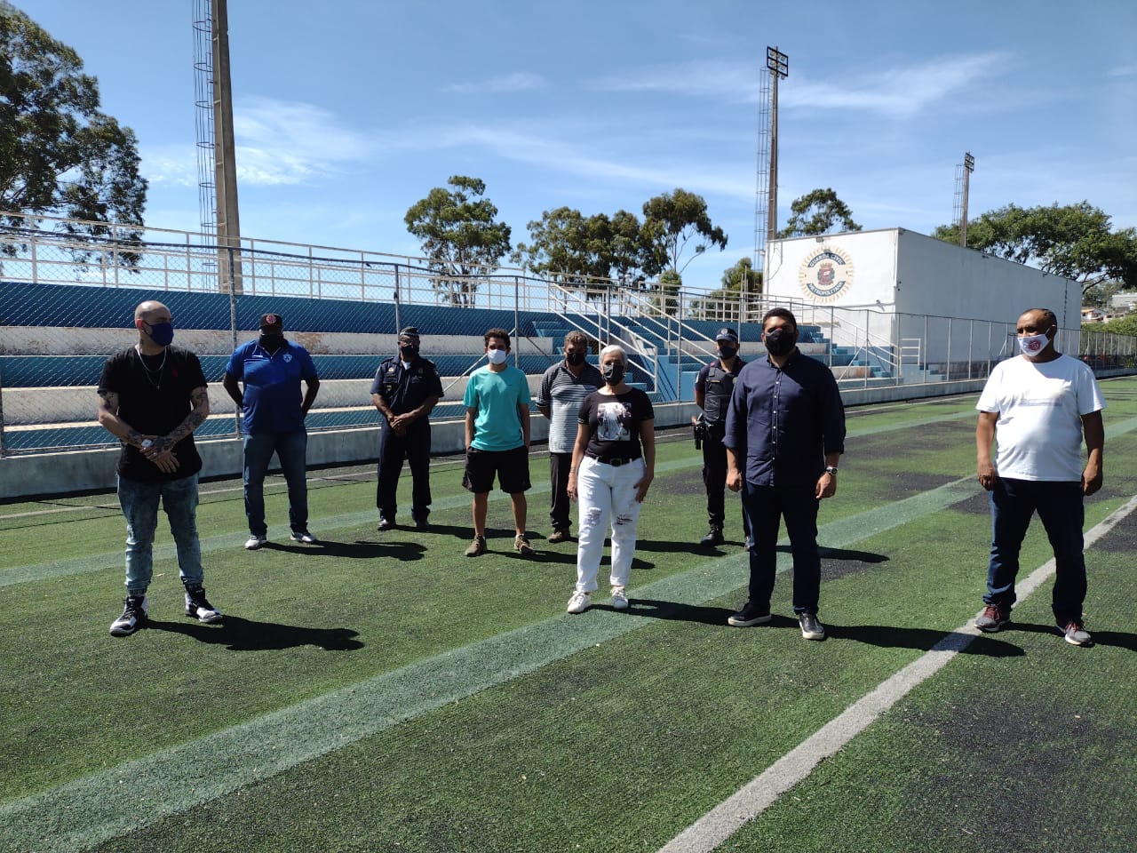 Secretário Municipal de Esportes e Lazer, Thiago Milhim, posa para foto com servidores dentro do campo do Centro Esportivo Perus durante vistoria.