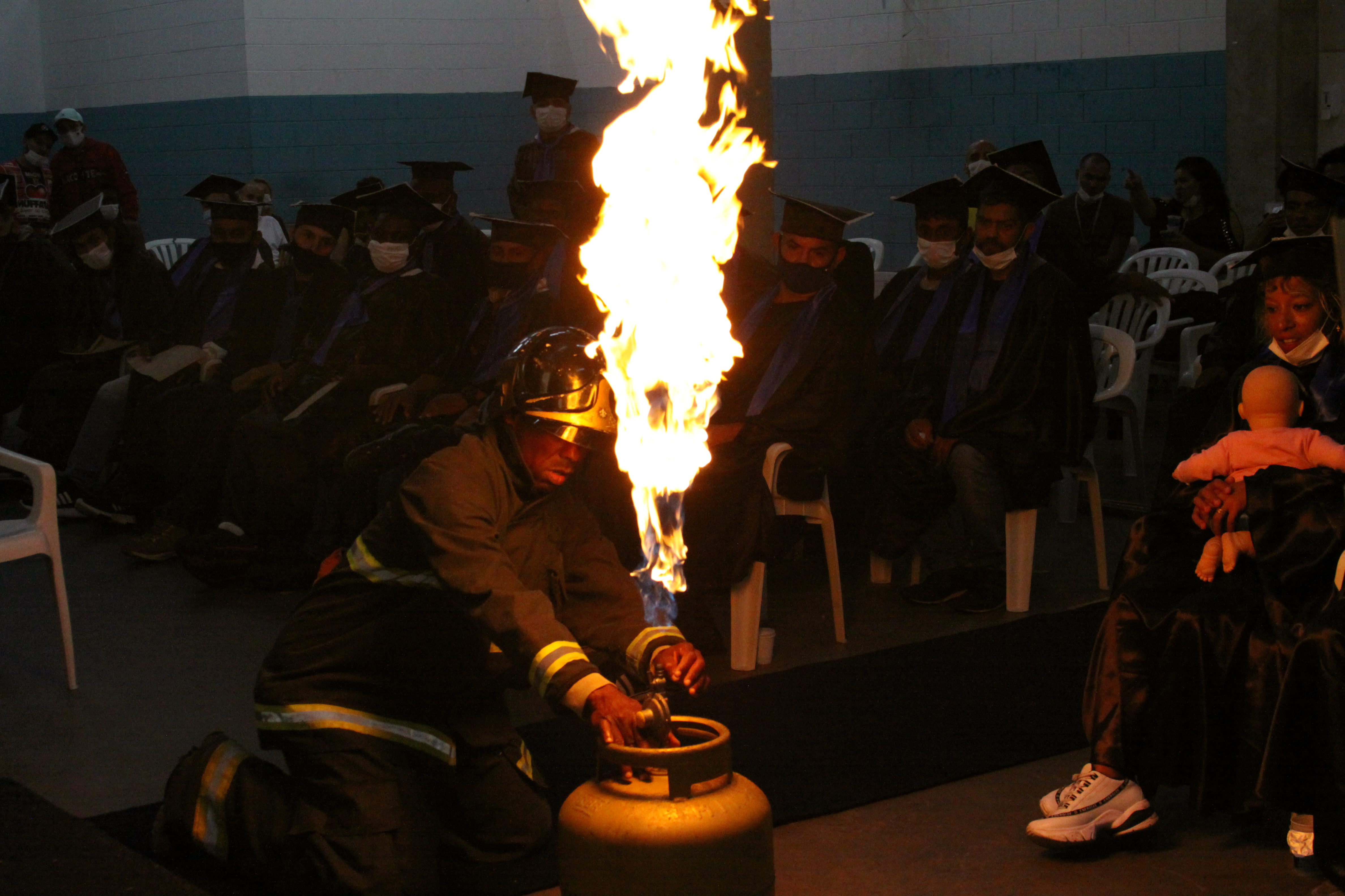  Encenação de Incêndio provocado por botijão de gás. Aluno do Curso Brigadista de Incêndio, devidamente equipado, apaga o fogo gerado em cerimônia de formatura do curso para uma demonstração.