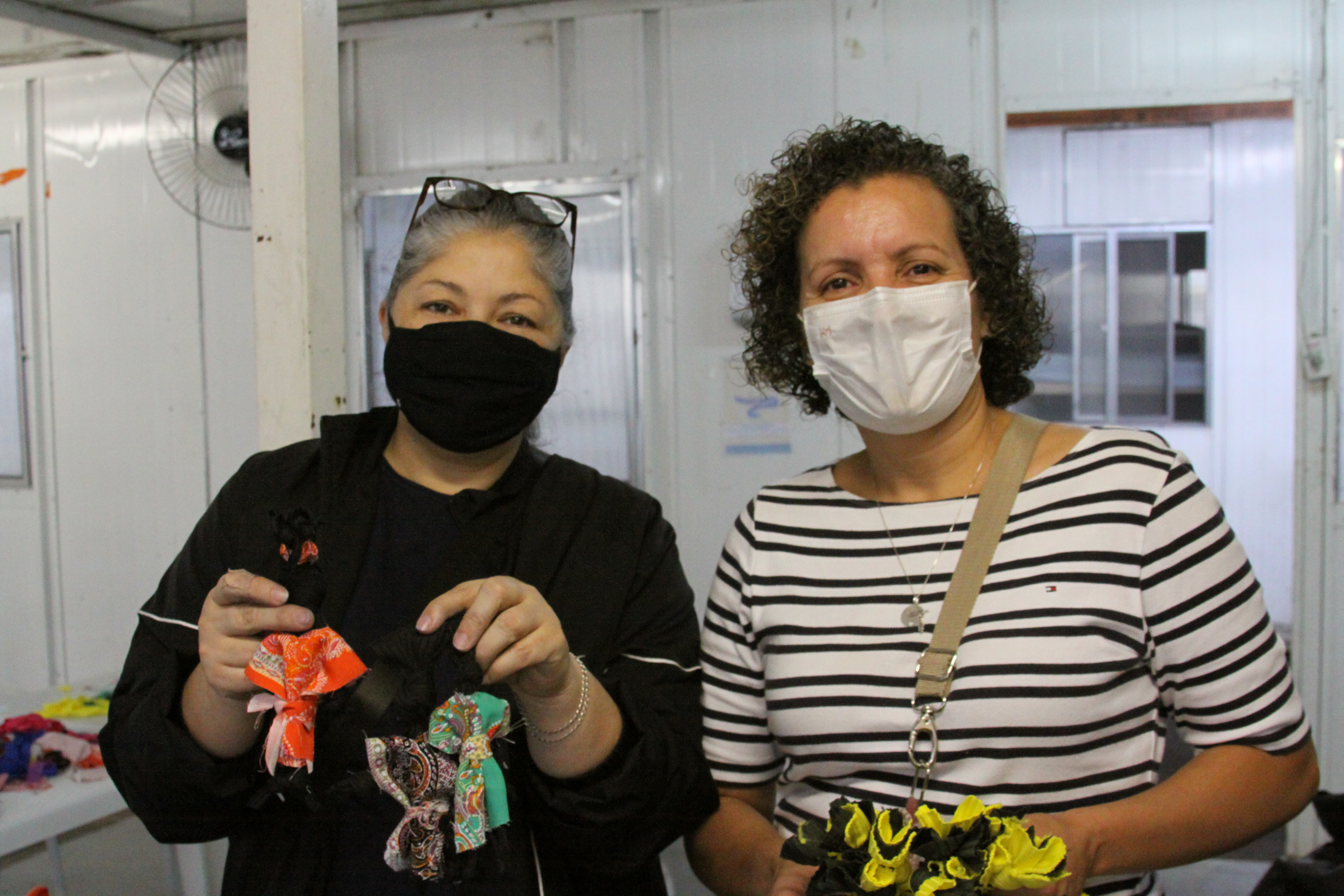 As orientadoras da oficina, Patrícia Rodrigues e Simone Cavini, respectivamente, exibem as bonecas africanas e tapetes produzidos durante a aula. 
