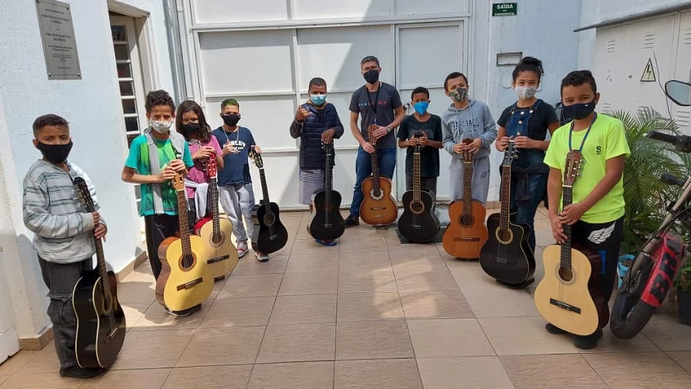 10 crianças, cada uma com seu violão e com suas máscaras, posam para foto durante uma das aulas de música realizadas no CCA.