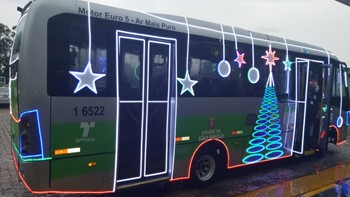 Imagem de ônibus iluminado, com estrelas e árvore de natal feitas com luzes