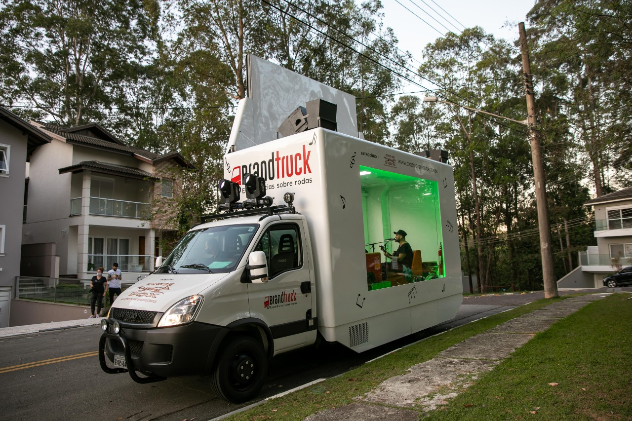 Foto do truck da campanha, com um cantor se apresentando, passando em frente a uma residência em um bairro na capital paulista.