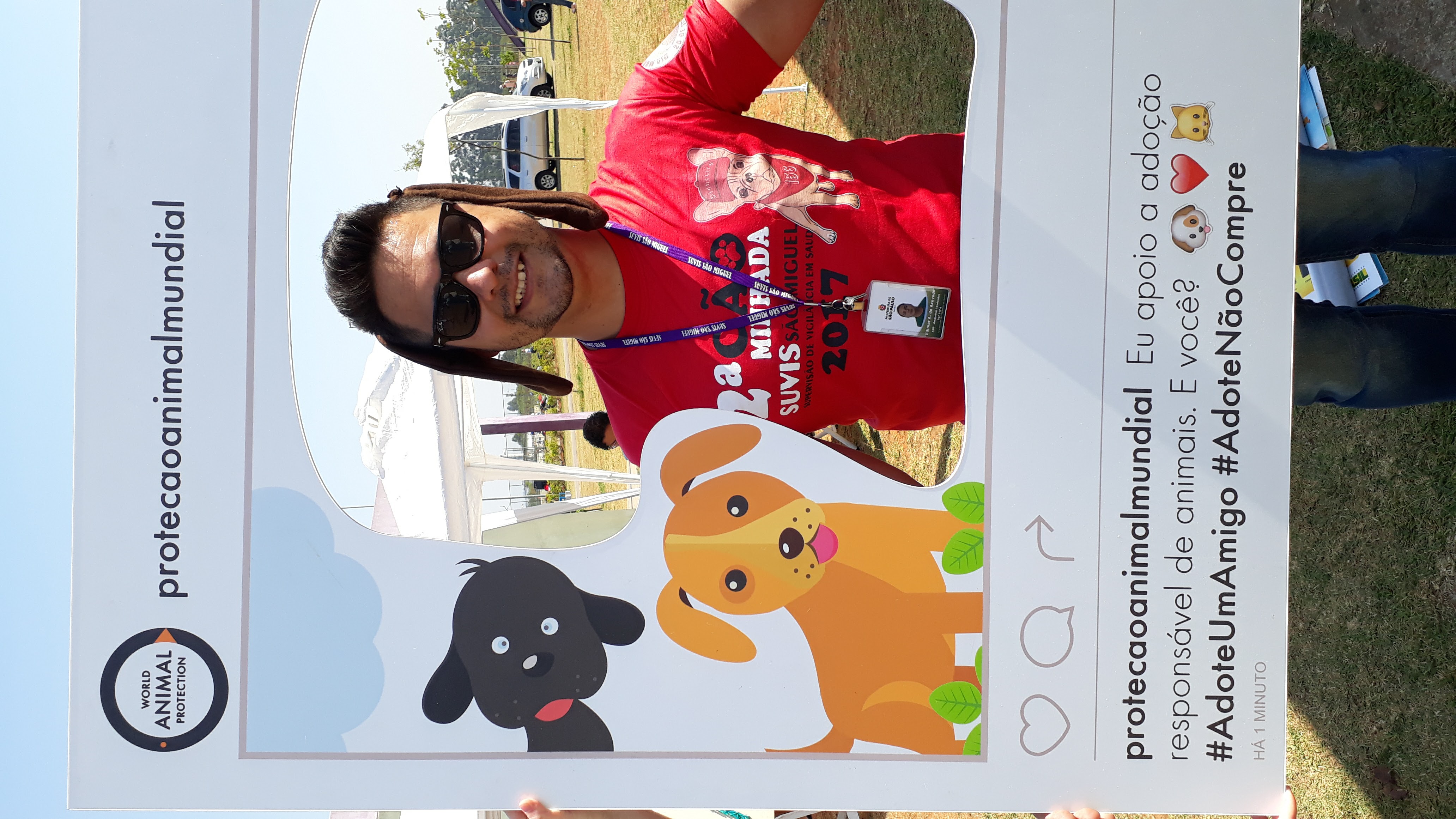 A foto mostra Edimar durante a Cãominhada de 2017; ele é um homem de cabelos escuros, usa óculos de sol e uma camiseta vermelha do evento e está com orelhas de cachorro, posando dentro de uma moldura que imita um post do aplicativo Instagram, onde se lê frases de incentivo à adoção de animais 