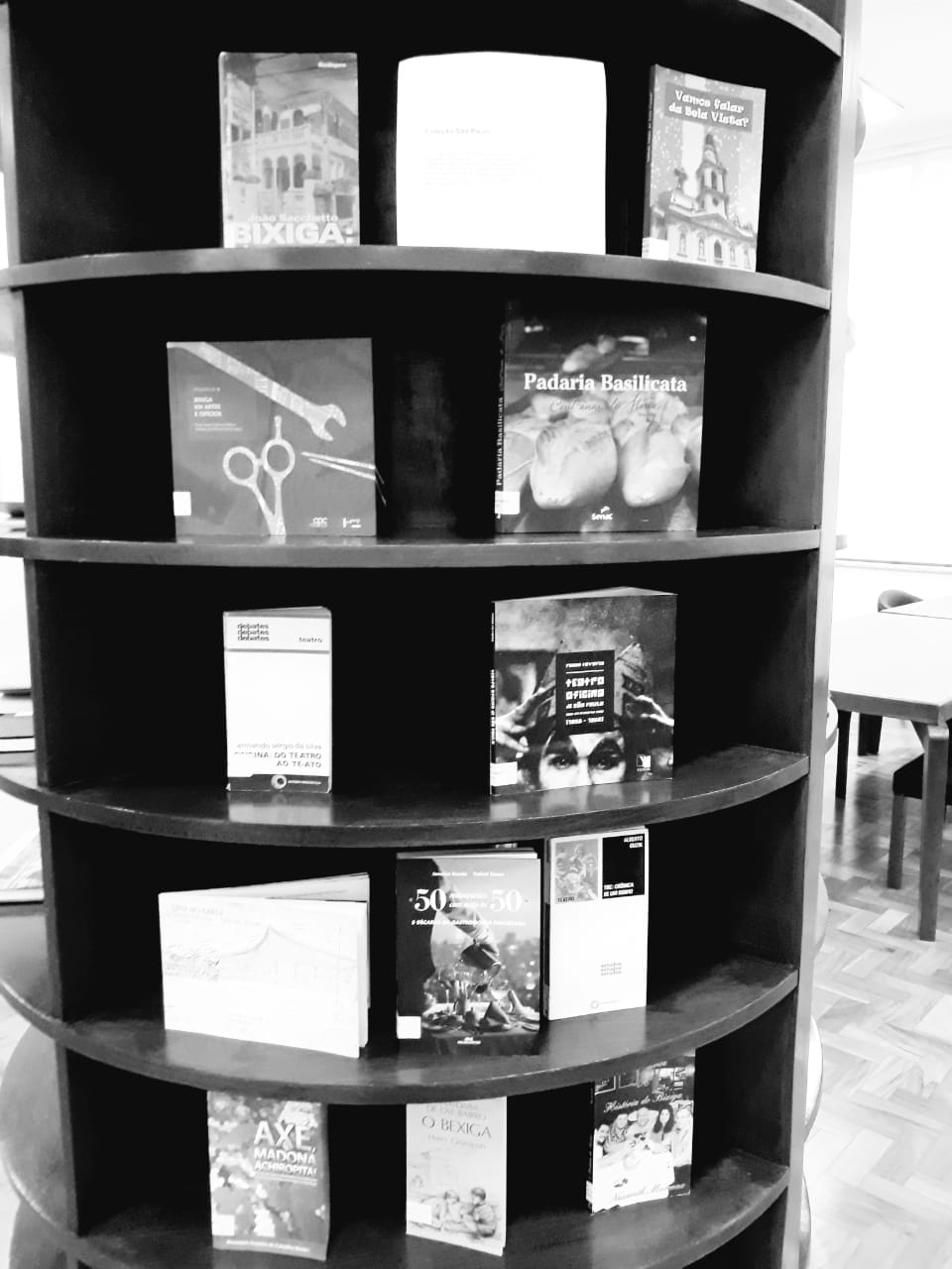 Foto em preto e branco dos livros expostos em móvel de madeira