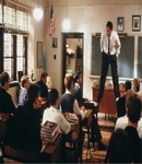 Sala de aula com professor em pé em cima de carteiras