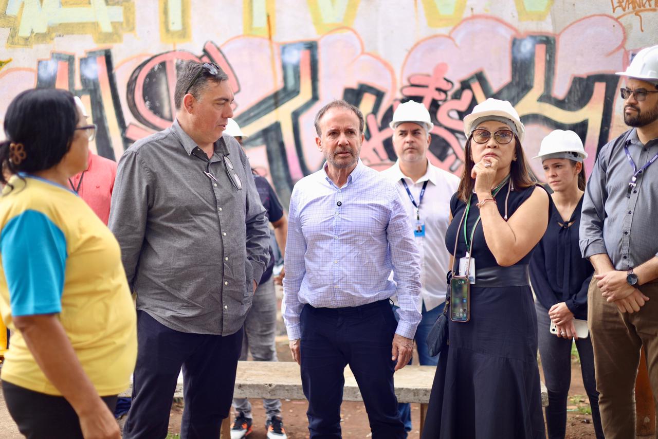 Esta é uma descrição da imagem, baseada no contexto fornecido sobre a visita de inspeção à obra da nova UBS Santa Luzia, em Guaianases, com a presença do Secretário Municipal da Saúde, Luiz Carlos Zamarco:  Descrição para Deficientes Visuais:  A imagem é uma fotografia tirada em um canteiro de obras, focando em um grupo de autoridades e técnicos que inspecionam a construção das novas instalações da Unidade Básica de Saúde (UBS) Santa Luzia.