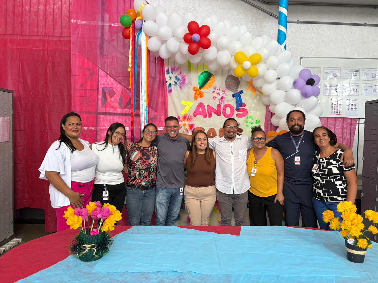 A imagem mostra um grupo de profissionais de saúde em frente a um painel com a frase