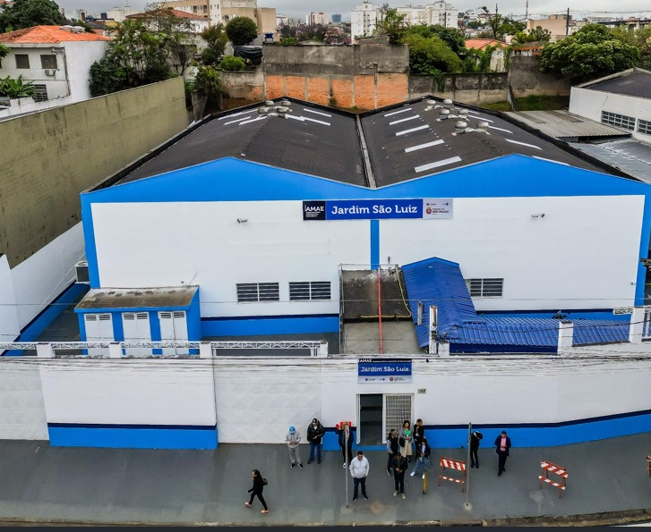 A imagem mostra a fachada de um prédio recém-reformado e bem conservado, com pintura predominante nas cores branca e azul. Na parte superior da fachada está escrito