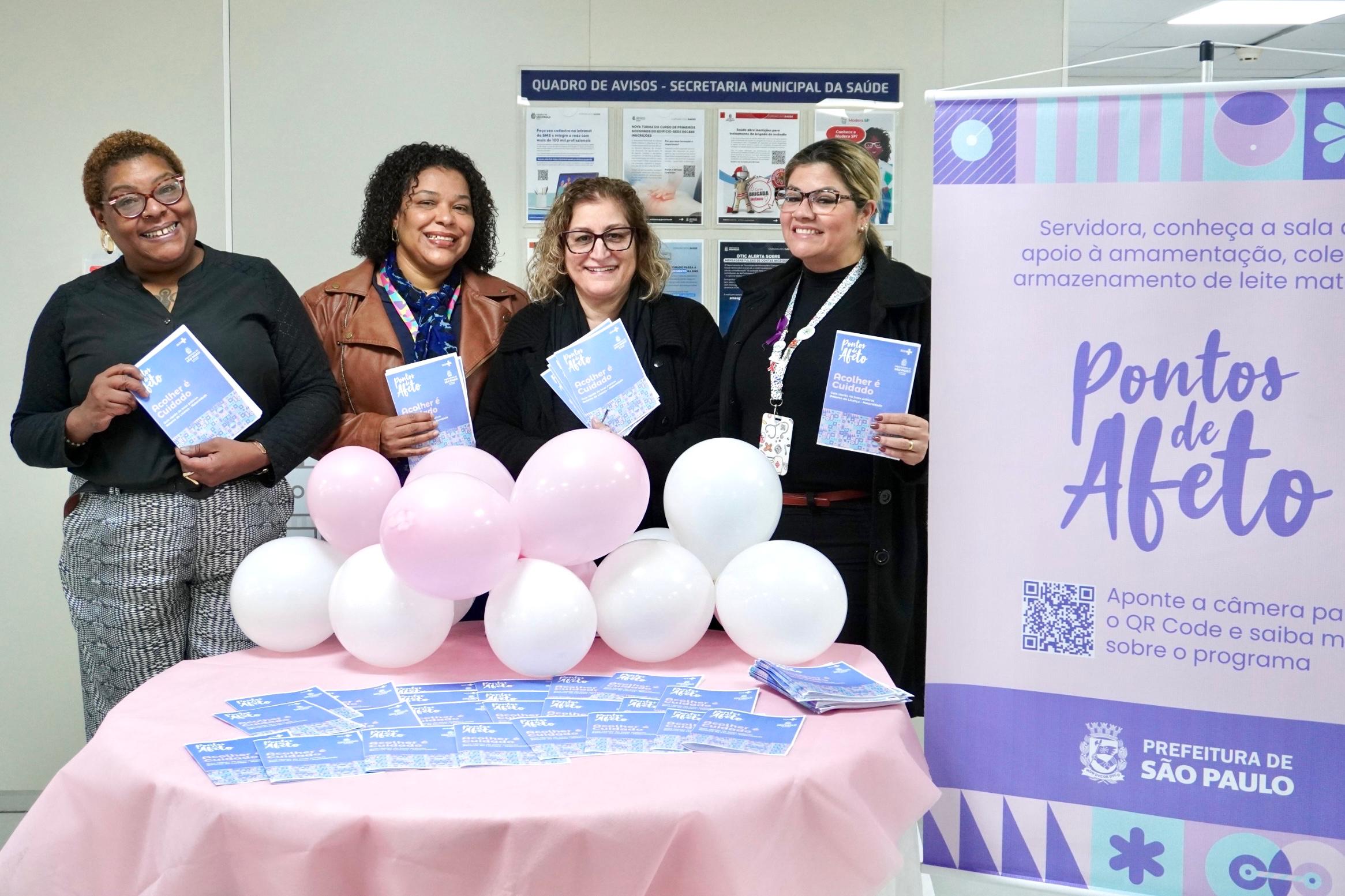 Quatro mulheres, integrantes da Equipe DDCQVT, estão segurando panfletos sobre o agosto dourado