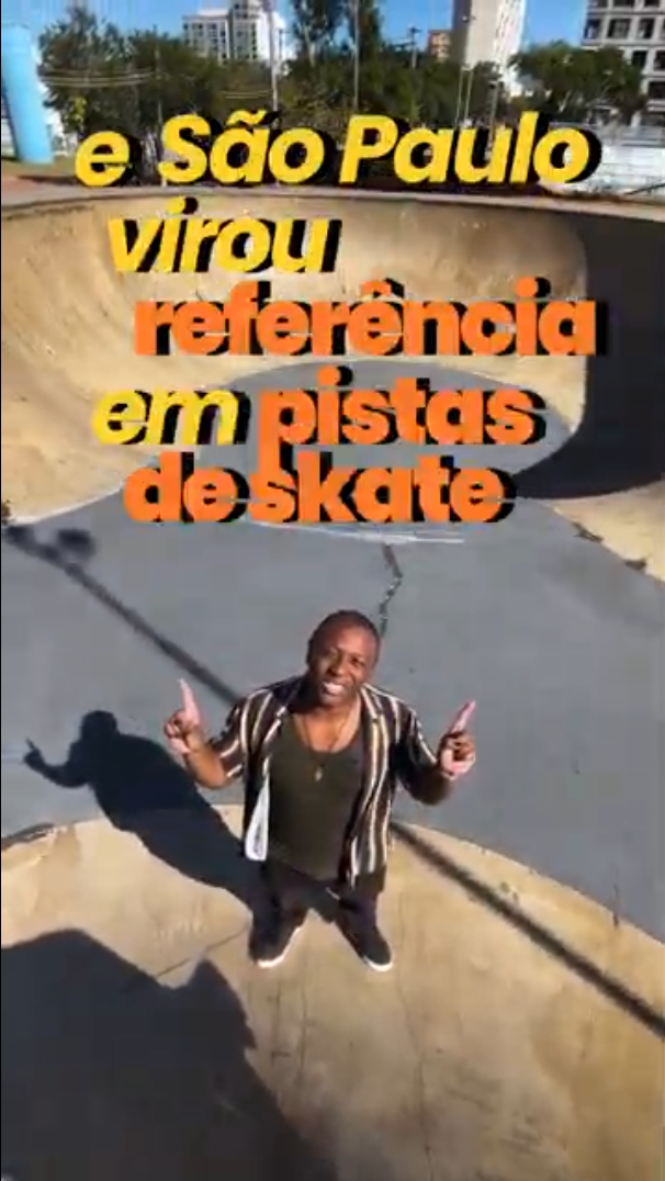 A imagem mostra uma pessoa em pé no centro de uma pista de skate do tipo bowl, com os dois polegares levantados. Ao fundo, é possível ver prédios, árvores e parte de uma área urbana. Sobre a imagem, há um texto em destaque que diz: "e São Paulo virou referência em pistas de skate", com as palavras em amarelo e laranja. A cena transmite um clima de orgulho em relação à infraestrutura de skate na cidade de São Paulo.