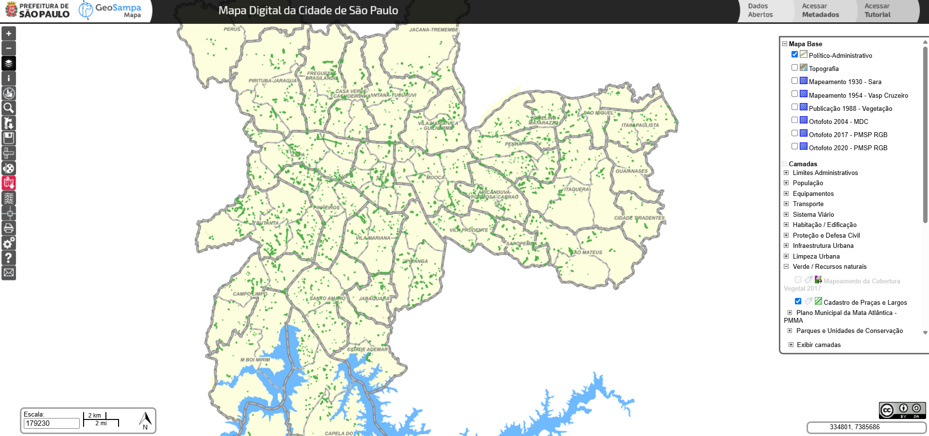 A imagem é uma captura de tela do GeoSampa, o mapa digital da cidade de São Paulo, disponibilizado pela Prefeitura. O mapa está com a camada “Cadastro de Praças e Largos” ativada, destacando em verde a localização dessas áreas em toda a cidade. A base cartográfica selecionada é a “Político-Administrativa”, mostrando os limites dos distritos paulistanos, com seus nomes claramente legíveis. O painel lateral direito permite a seleção de diversas camadas adicionais, como vegetação, habitação, sistema viário e infraestrutura urbana, entre outros. A visualização atual também destaca áreas de mananciais ao sul do município.
