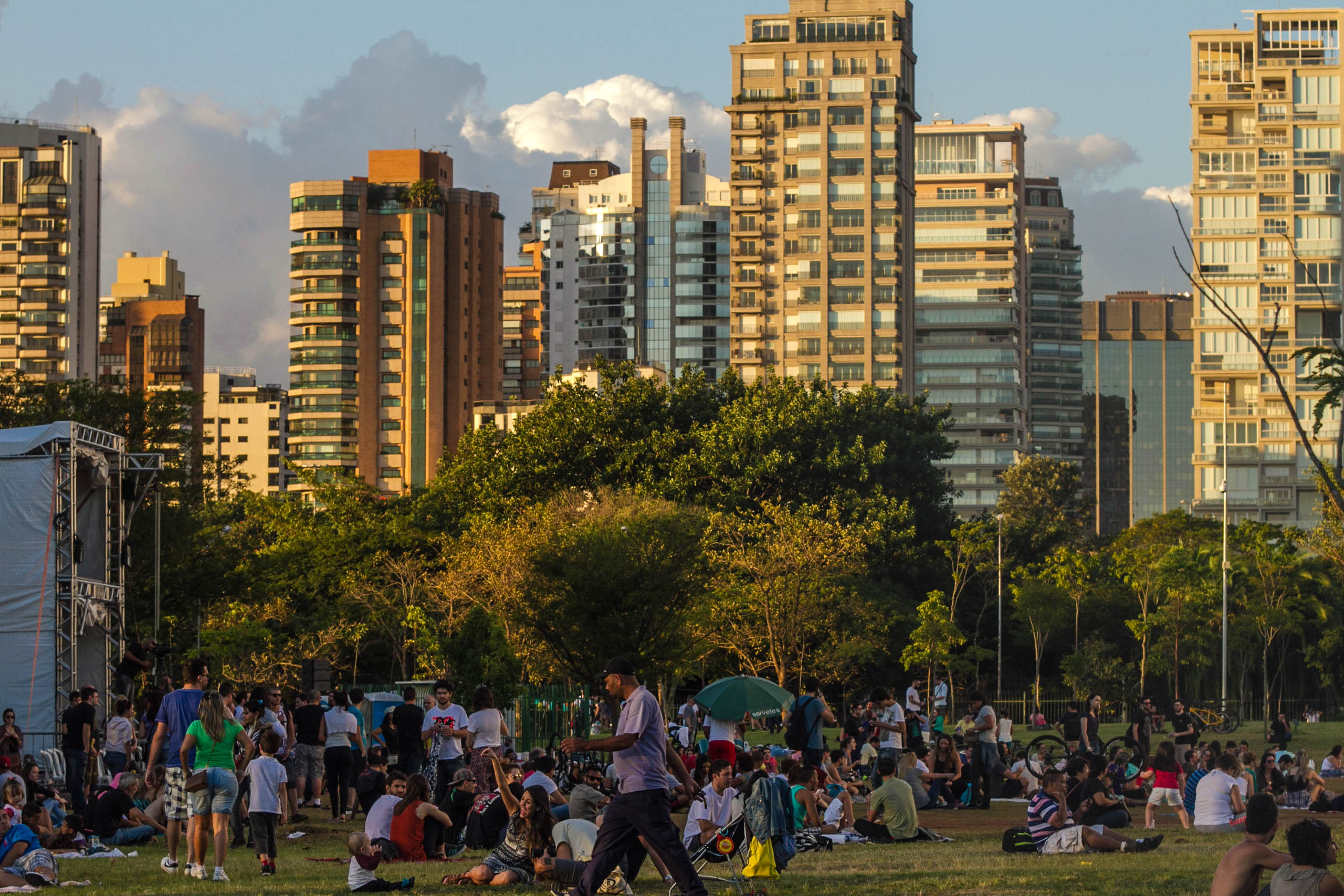 Grandes prédios cercando um parque com muitas árvores e pessoas