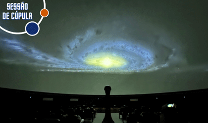 A imagem mostra o interior de uma cúpula e no teto é exibida uma galáxia em tons de azul e amarelo. No canto superior esquerdo, o logotipo da Sessão de Cúpula.