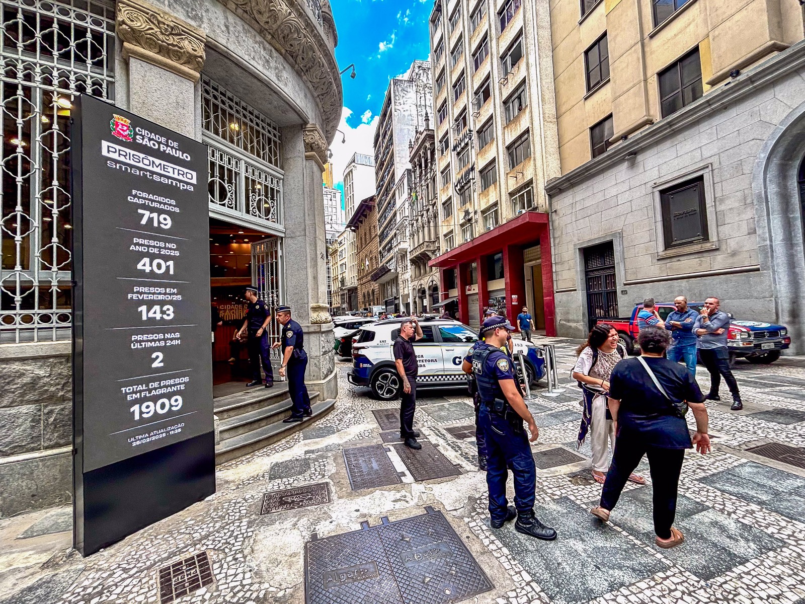 Guardas Municipais ao lado da tela de led na cor preta, que contabiliza os números do Smart Sampa.
