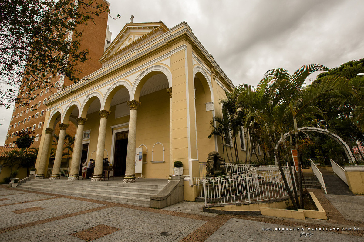 Imagem da fachada da Paróquia São José do Ipiranga. A entrada está nas cores amarela e branca com um coqueiro a direita.