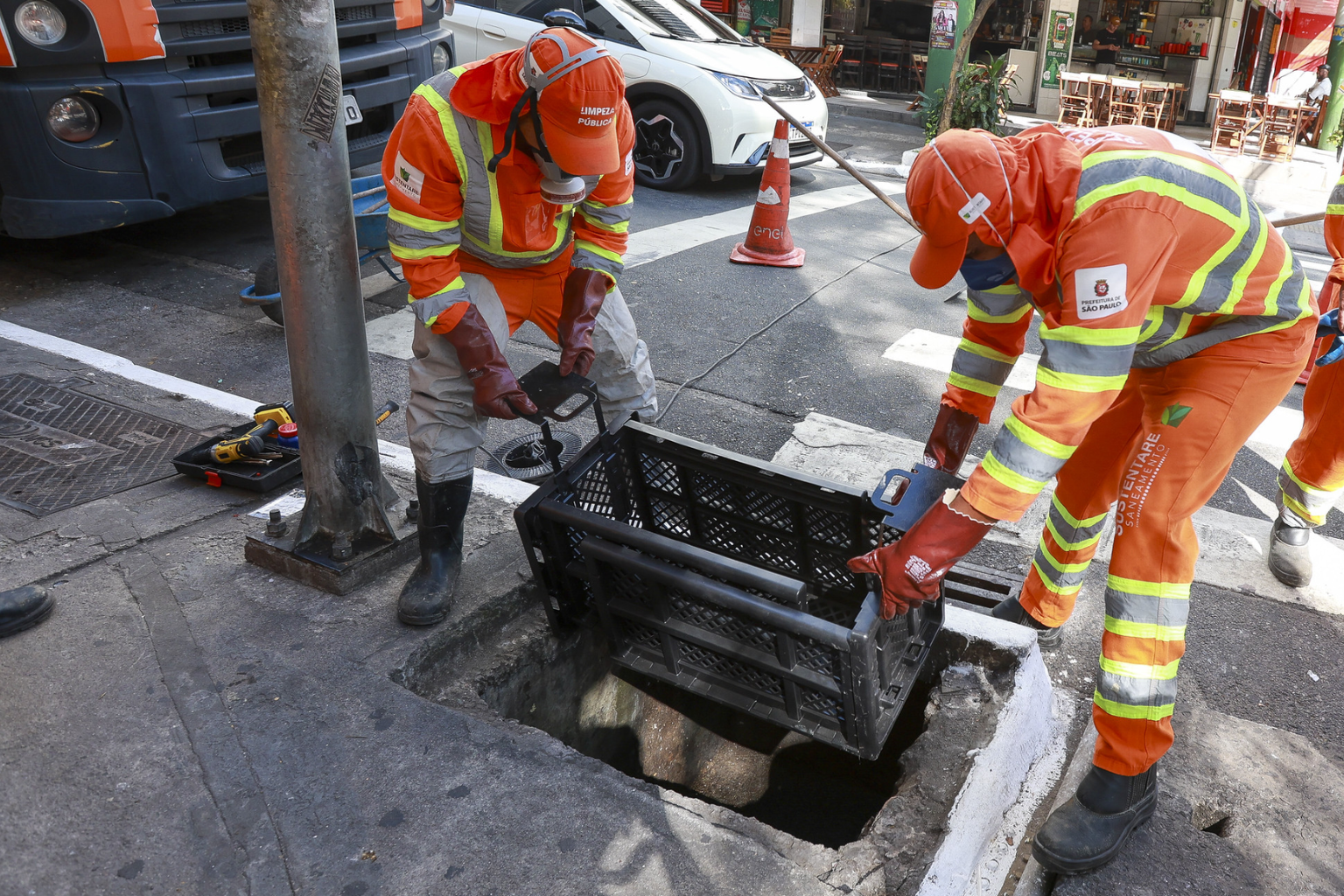 Agentes da Prefeitura de São Paulo realizando a limpeza de bueiros. 