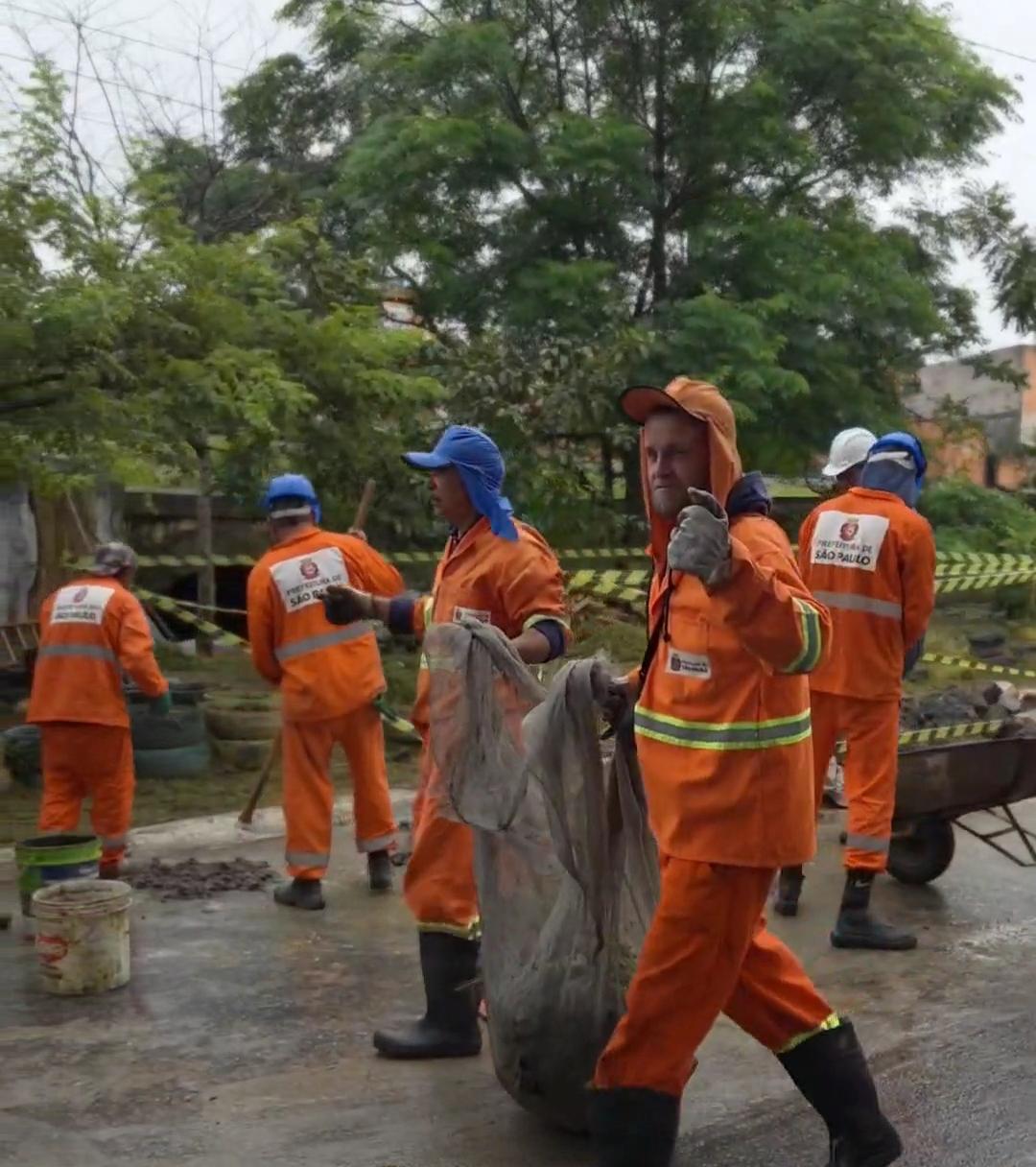 Trabalhadores da limpeza urbana realizam serviços de manutenção em área pública durante a Operação São Paulo Limpa, recolhendo resíduos e executando ações de zeladoria com apoio de equipamentos de trabalho.