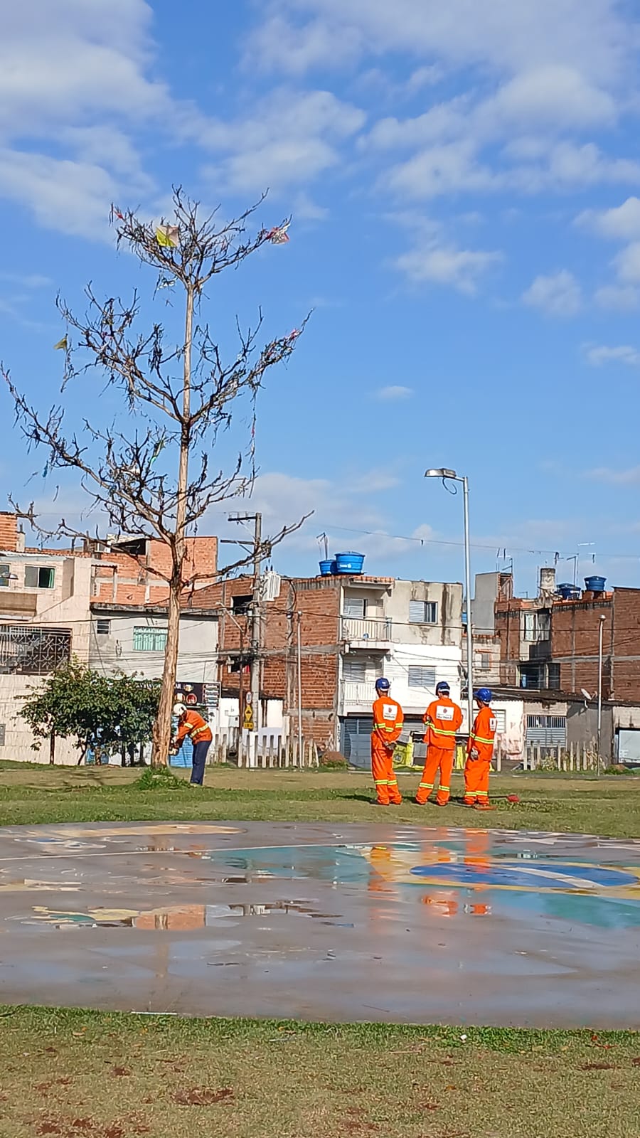 Equipes da Operação São Paulo Limpa realizam serviços de zeladoria em área pública. Na imagem, trabalhadores uniformizados executam manutenção e limpeza em uma praça, com destaque para a conservação de áreas verdes e dos espaços de convivência da comunidade.