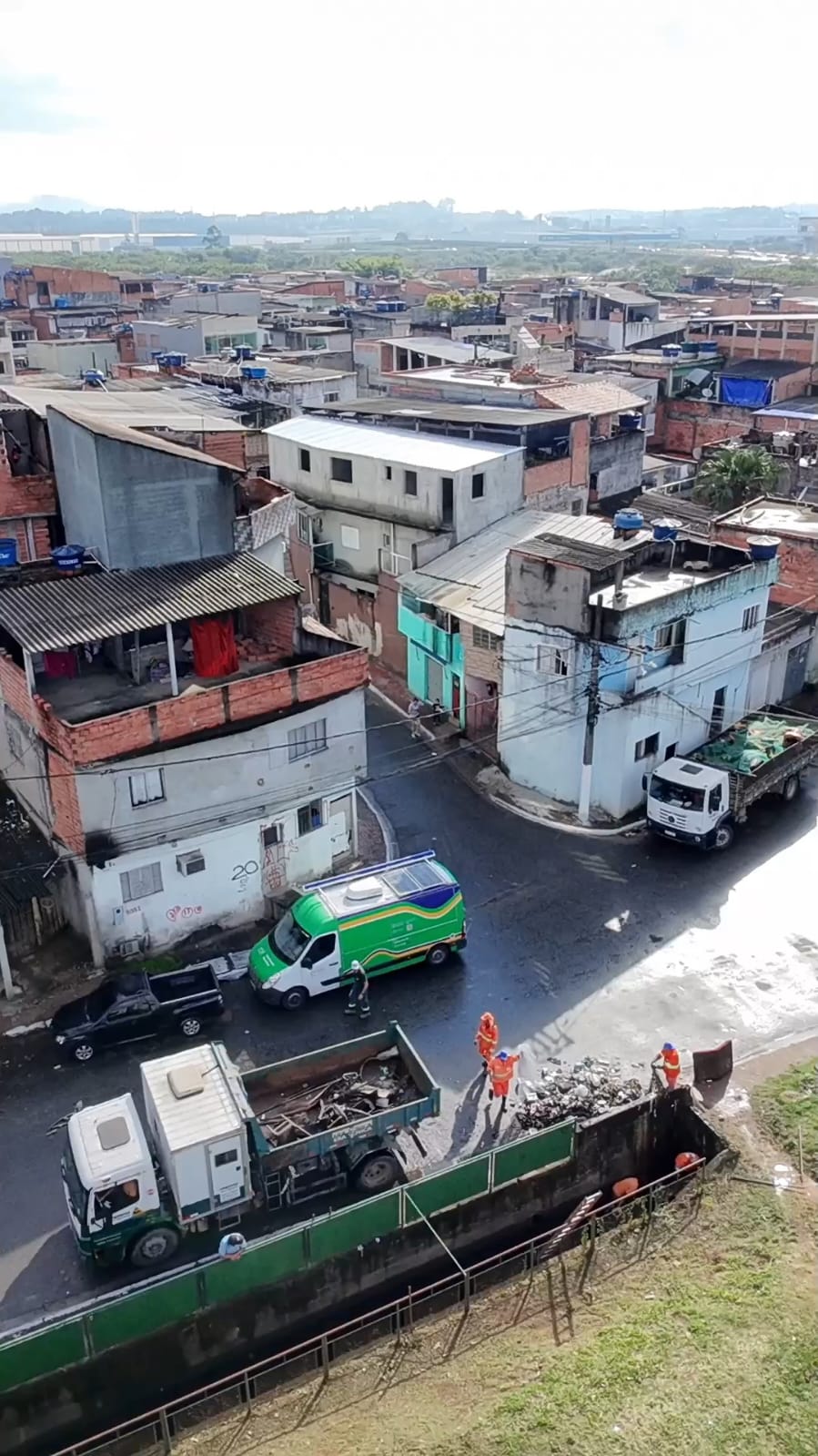 Equipes realizam serviços de limpeza e remoção de resíduos durante o projeto Recupera Pantanal. Na imagem, caminhões e trabalhadores atuam em uma via próxima a uma área residencial, recolhendo materiais descartados e contribuindo para a recuperação ambiental e a melhoria dos espaços públicos da região.